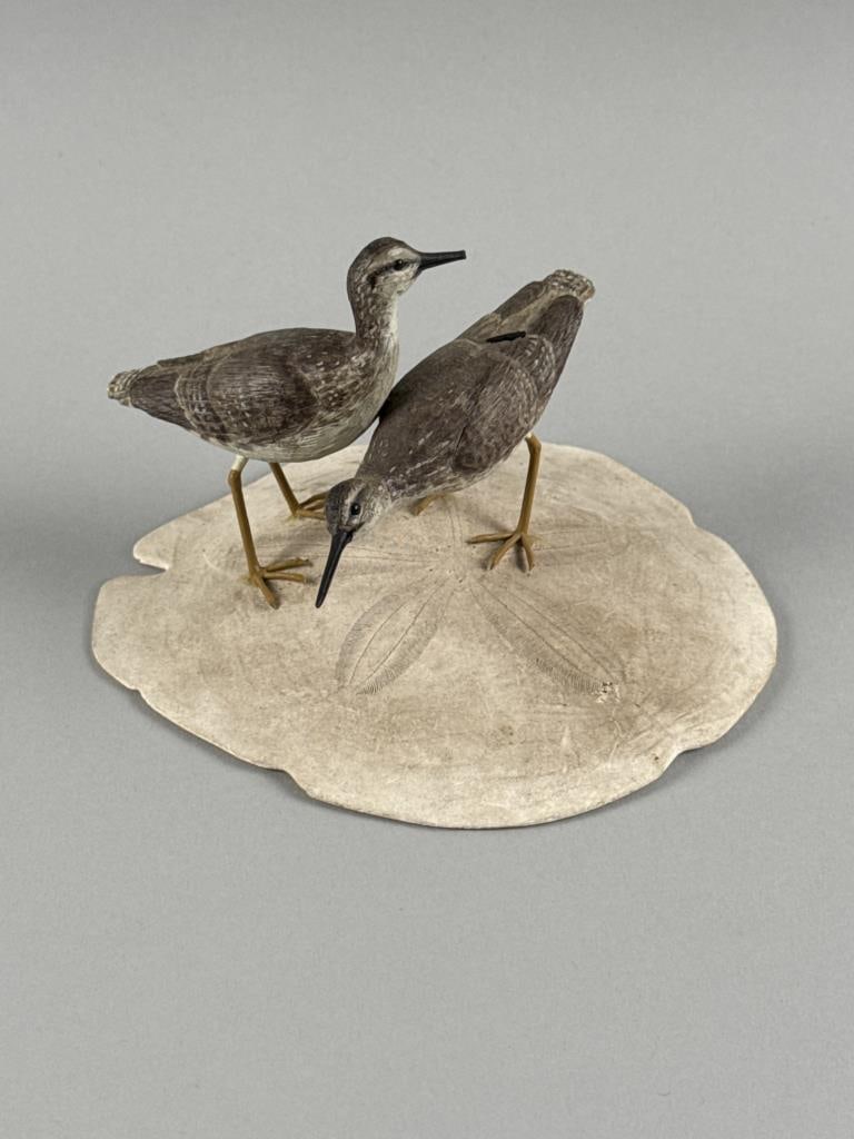 PAIR OF STAN SPARRE MINIATURE YELLOWLEGS East Falmouth, Massachusetts, 1923-2011 Height 4".: PAIR OF STAN SPARRE MINIATURE YELLOWLEGS East Falmouth, Massachusetts, 1923-2011 Mounted together on a sand dollar base. Signed on underside. Height 4".