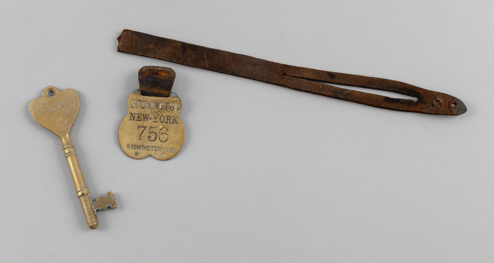 STATEROOM KEY AND A STONINGTON-NEW YORK LINE LUGGAGE TAG 19th Century Lengths 4" and 11.5".: STATEROOM KEY AND A STONINGTON-NEW YORK LINE LUGGAGE TAG 19th Century Brass key for a Rhode Island ship stateroom. Brass luggage tag on a leather strap Lengths 4" and 11.5".