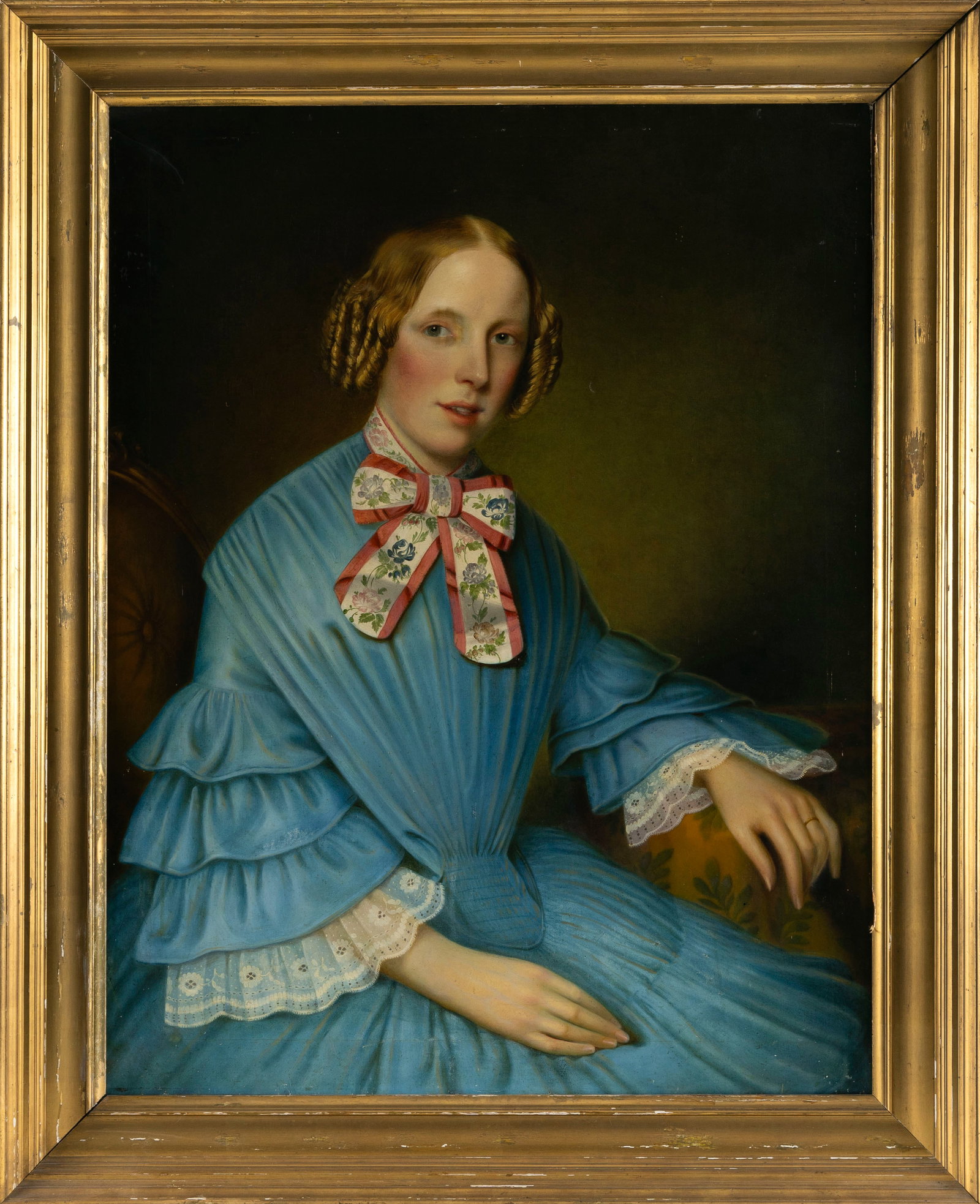 AMERICAN SCHOOL (19th Century,), Portrait of a woman, Oil on canvas, 35" x 27". Framed 42" x 33".: AMERICAN SCHOOL 19th Century Portrait of a woman wearing a vibrant blue dress with ruffled sleeves and intricate white lace cuffs. A large floral patterned bow is tied around her neck. Oil on canvas, 