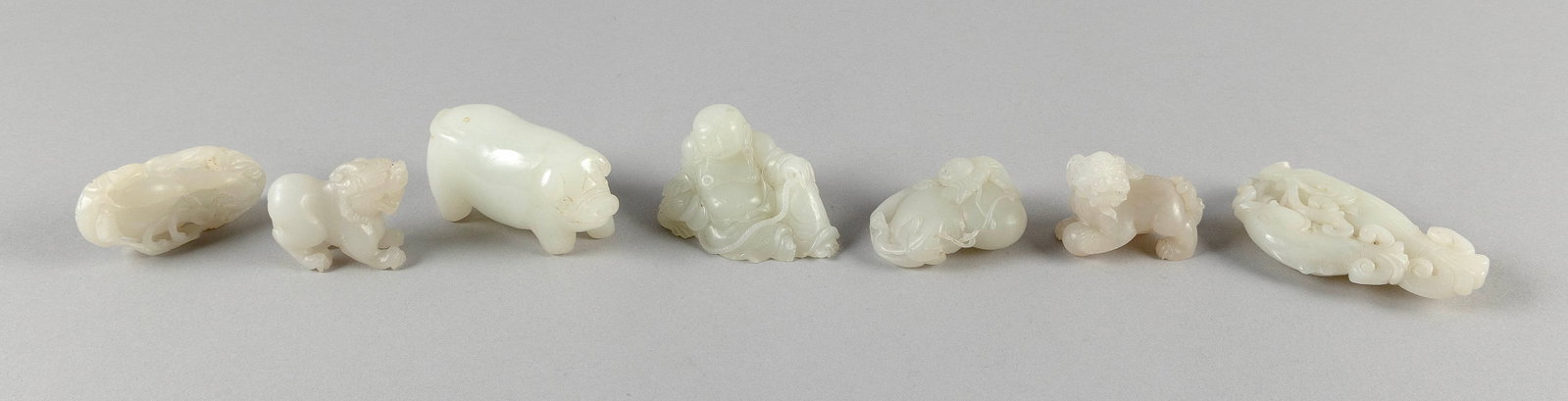 SEVEN CARVED WHITE JADE FINGERING AND OTHER PIECES Lengths from 2" to 3.25".: SEVEN CARVED WHITE JADE FINGERING AND OTHER PIECES 1) Pig. 2) Two carp with grasses. 3) Hotei. 4) Fu dog with ball. 5) Fu dog without ball. 6) Boy climbing a gourd. 7) Double gourd and vines. Lengths 