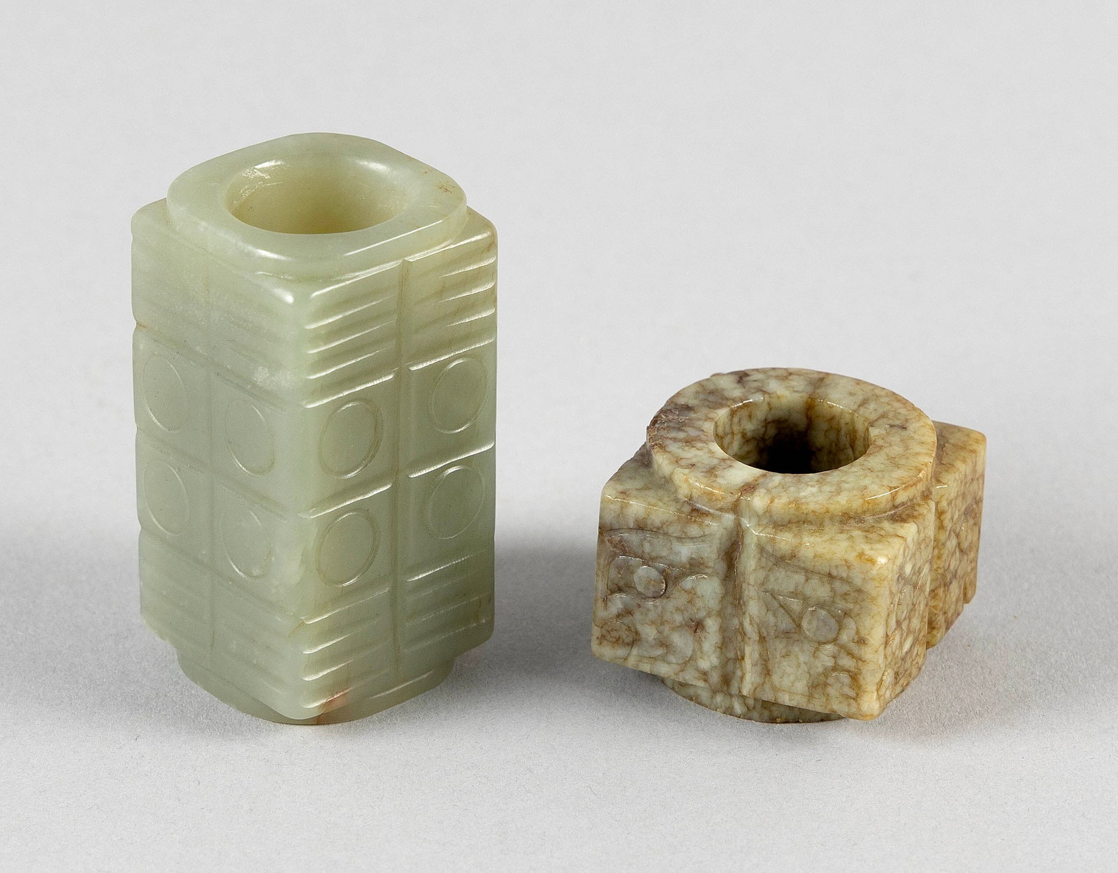 TWO CHINESE CARVED JADE CONG: TWO CHINESE CARVED JADE CONG 1) Archaic-style mottled jade with taotie mask design. Height 1". 2) Celadon jade with trigram and circle design. Height 2".