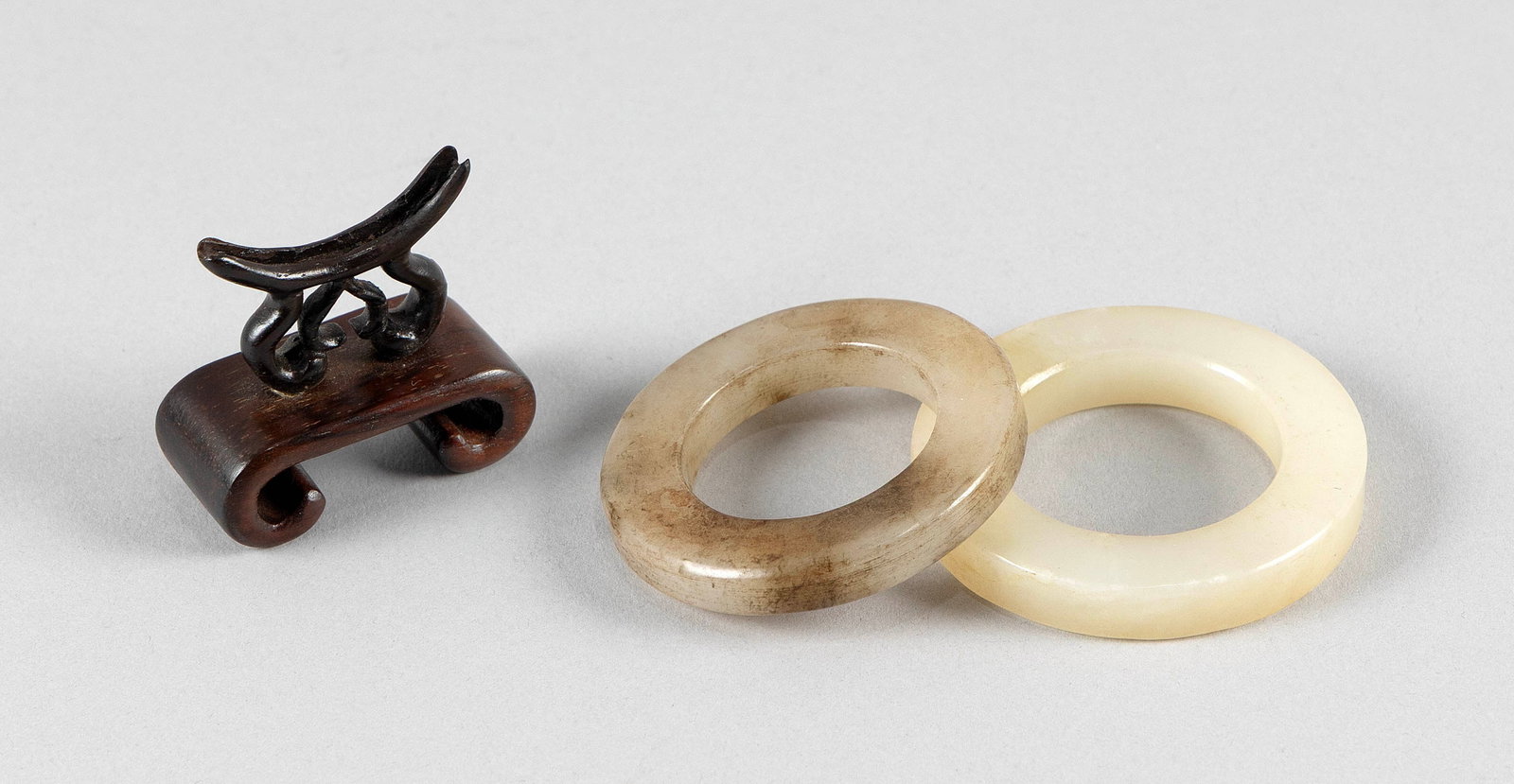 TWO CHINESE JADE BI WITH ONE WOOD STAND Diameters 2" and 2.25". (1 of 2)