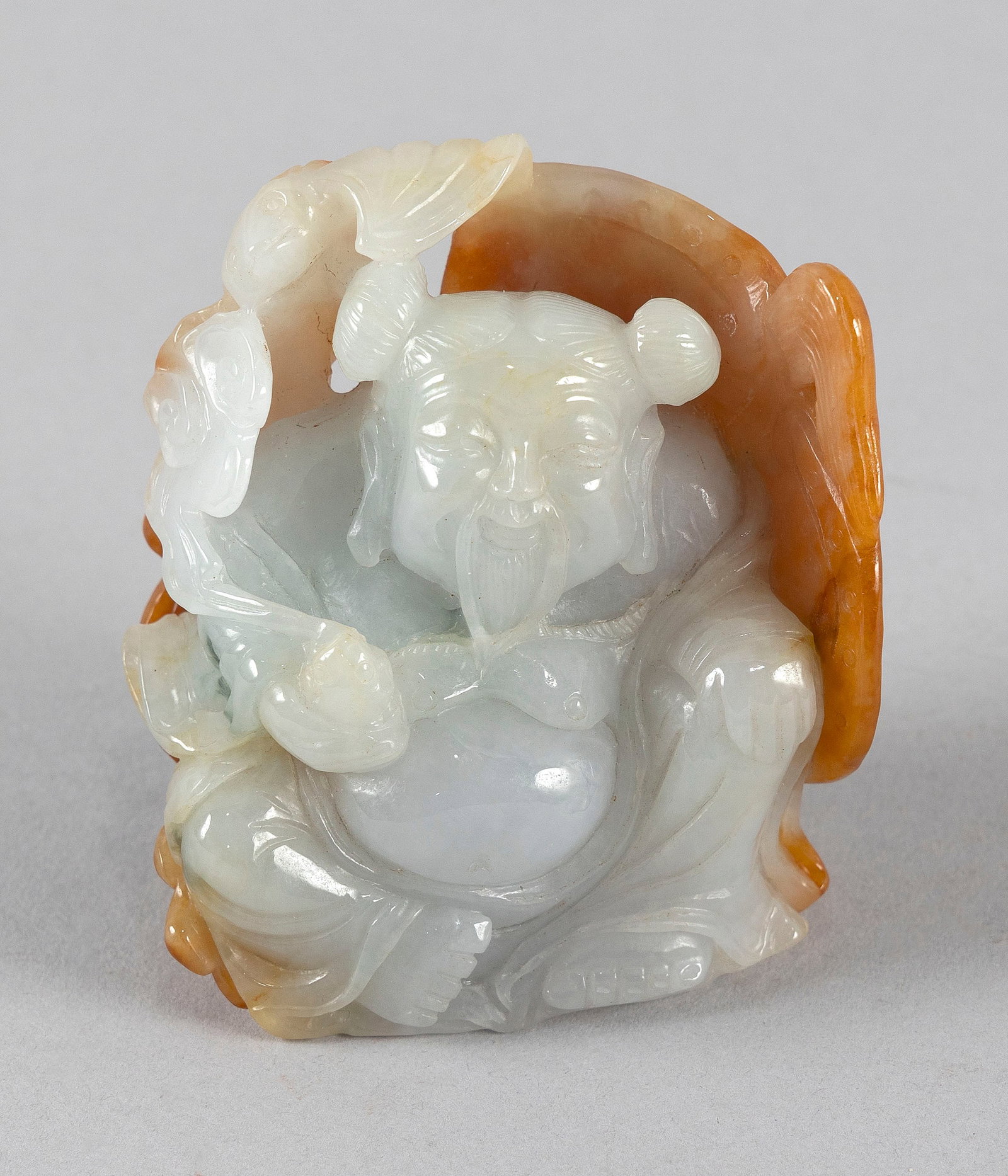CHINESE CARVED JADE SEATED BUDDHA Height 3".: CHINESE CARVED JADE SEATED BUDDHA Holding a stalk of ruyi and wrapped in a leaf with russet skin tones. Height 3".