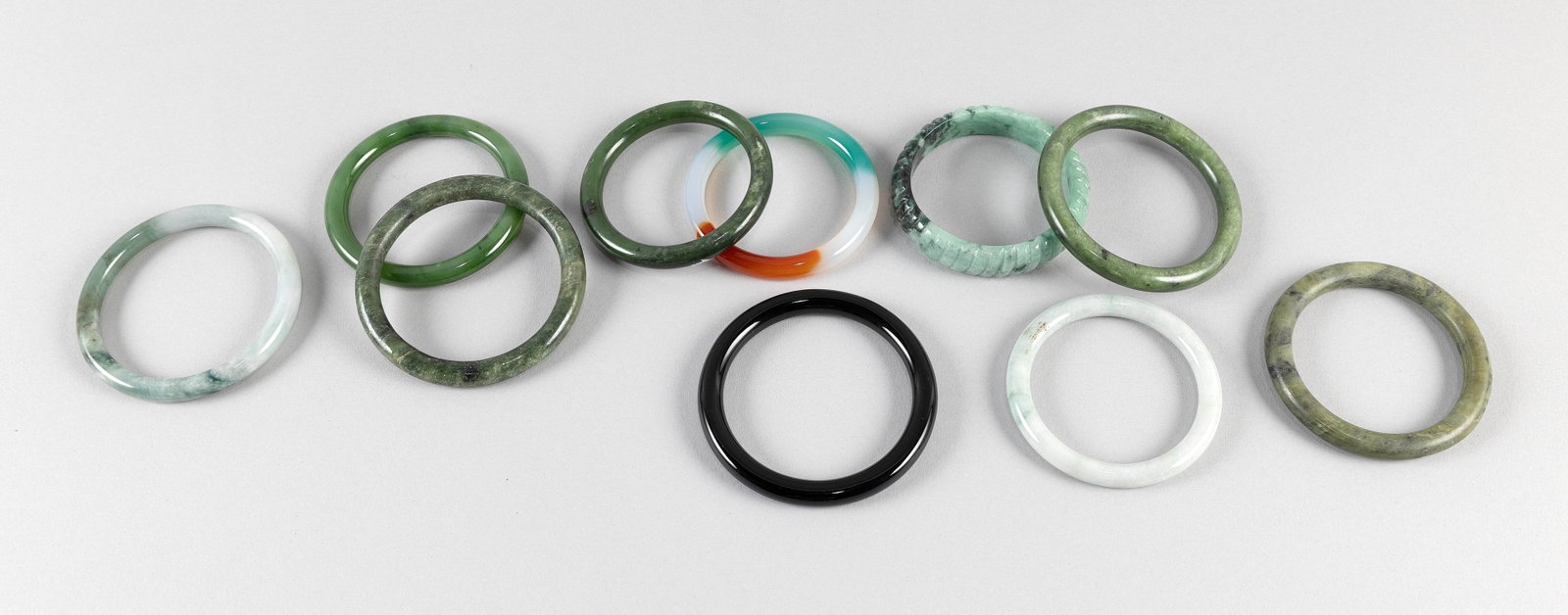 COLLECTION OF TEN JADE AND HARDSTONE BANGLES Diameters approx. 3".: COLLECTION OF TEN JADE AND HARDSTONE BANGLES Mostly green, but one with lavender and red coloring and another all black. Diameters approx. 3".