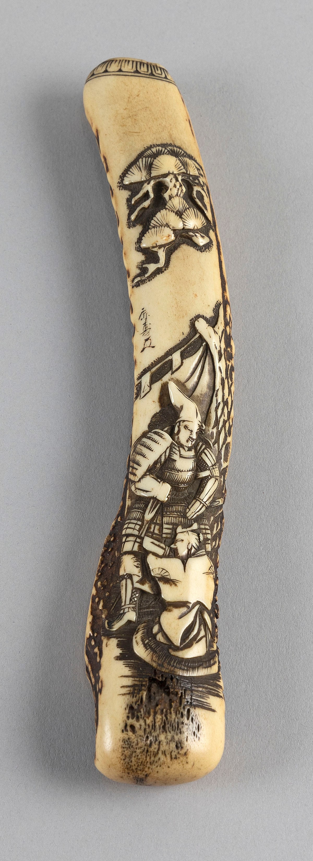 JAPANESE STAGHORN PIPE CASE SIGNED SANSEIDO Early 19th Century Length 7.75".: JAPANESE STAGHORN PIPE CASE SIGNED SANSEIDO Early 19th Century Decoration of two Samurai with weapons drawn under a large pine tree. Rim with a geometric pattern. Marked on front with kakihan. Signed 