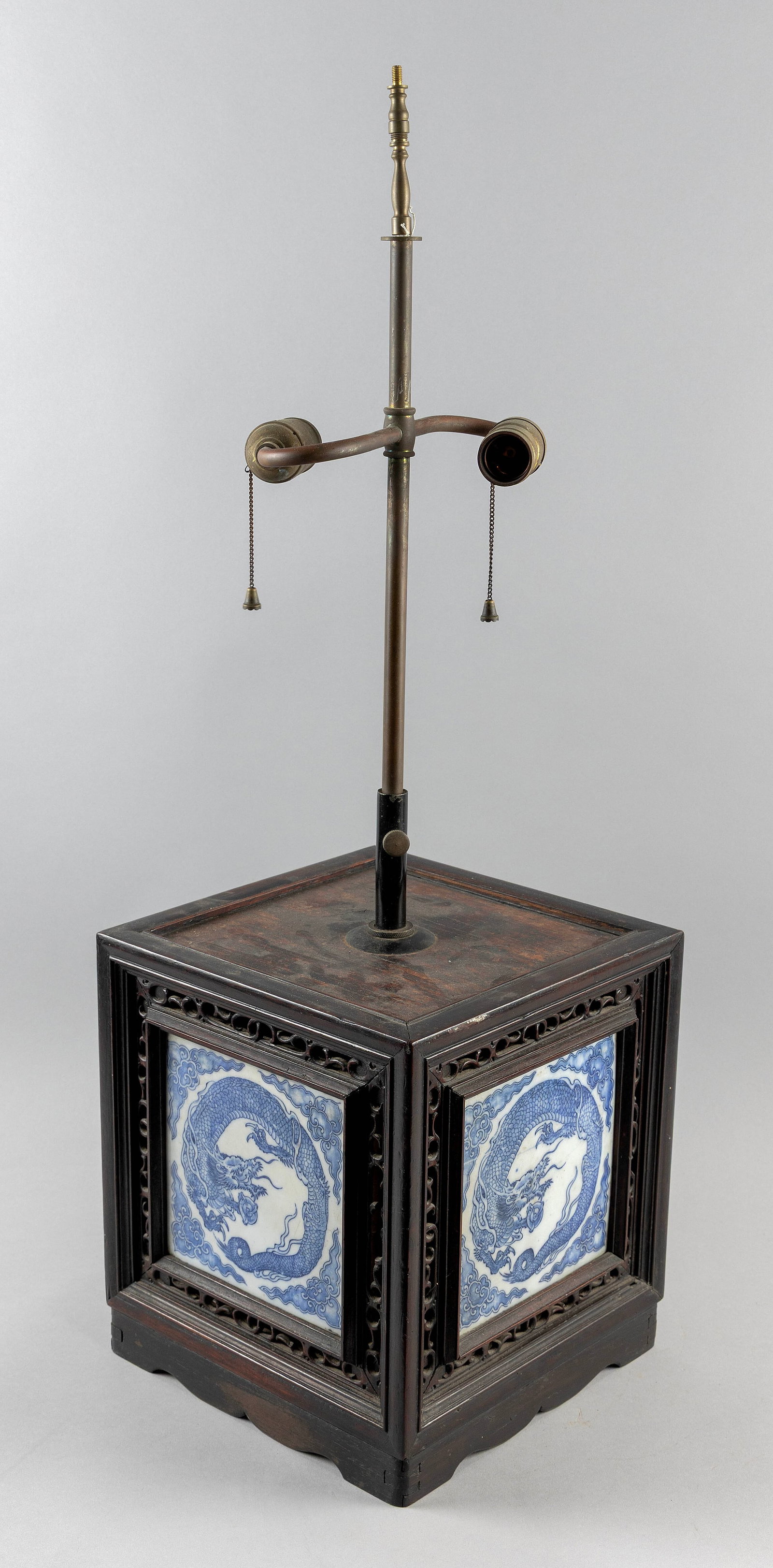 JAPANESE CARVED WOOD AND BLUE AND WHITE PORCELAIN SQUARE CANISTER 19th Century Canister height 11".: JAPANESE CARVED WOOD AND BLUE AND WHITE PORCELAIN SQUARE CANISTER 19th Century Inset porcelain panels depict dragons and pearl rondels. Mounted as a lamp. Canister height 11". Top 10" x 10". Provenanc