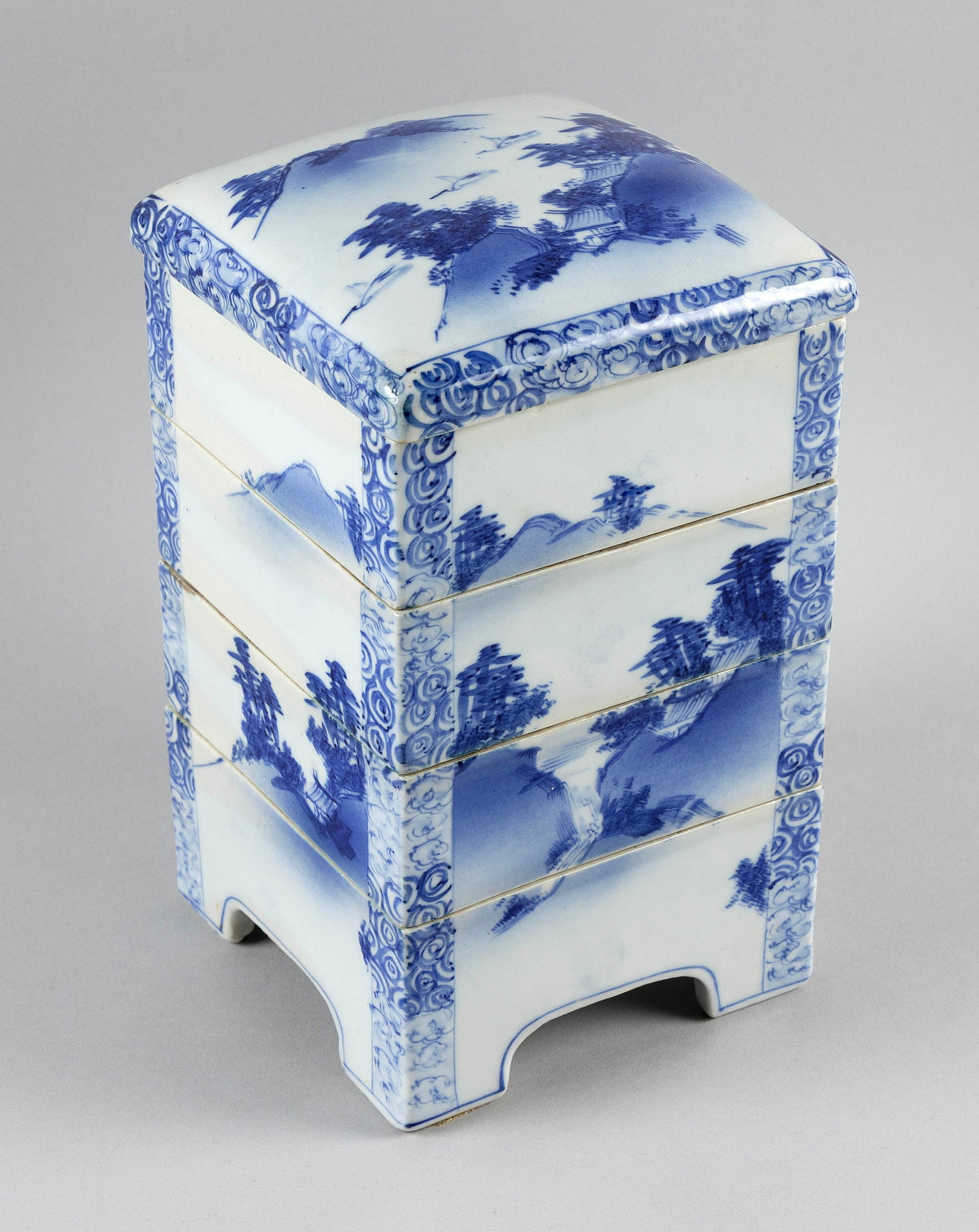 JAPANESE BLUE AND WHITE PORCELAIN FOUR-TIER JUBAKO Late 19th/Early 20th Century Height 10". Length: JAPANESE BLUE AND WHITE PORCELAIN FOUR-TIER JUBAKO Late 19th/Early 20th Century Continuous landscape decoration. Slightly domed cover. Height 10". Length 6". Width 6".