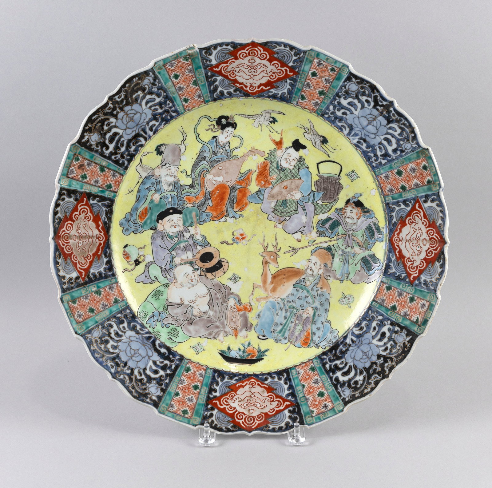JAPANESE IMARI PORCELAIN CHARGER Meiji Period Diameter 18".: JAPANESE IMARI PORCELAIN CHARGER Meiji Period Central decoration of the Seven Lucky Gods, deer, crane and other auspicious elements against a famille jaune ground. Shaped rim with brocade paneling. Di