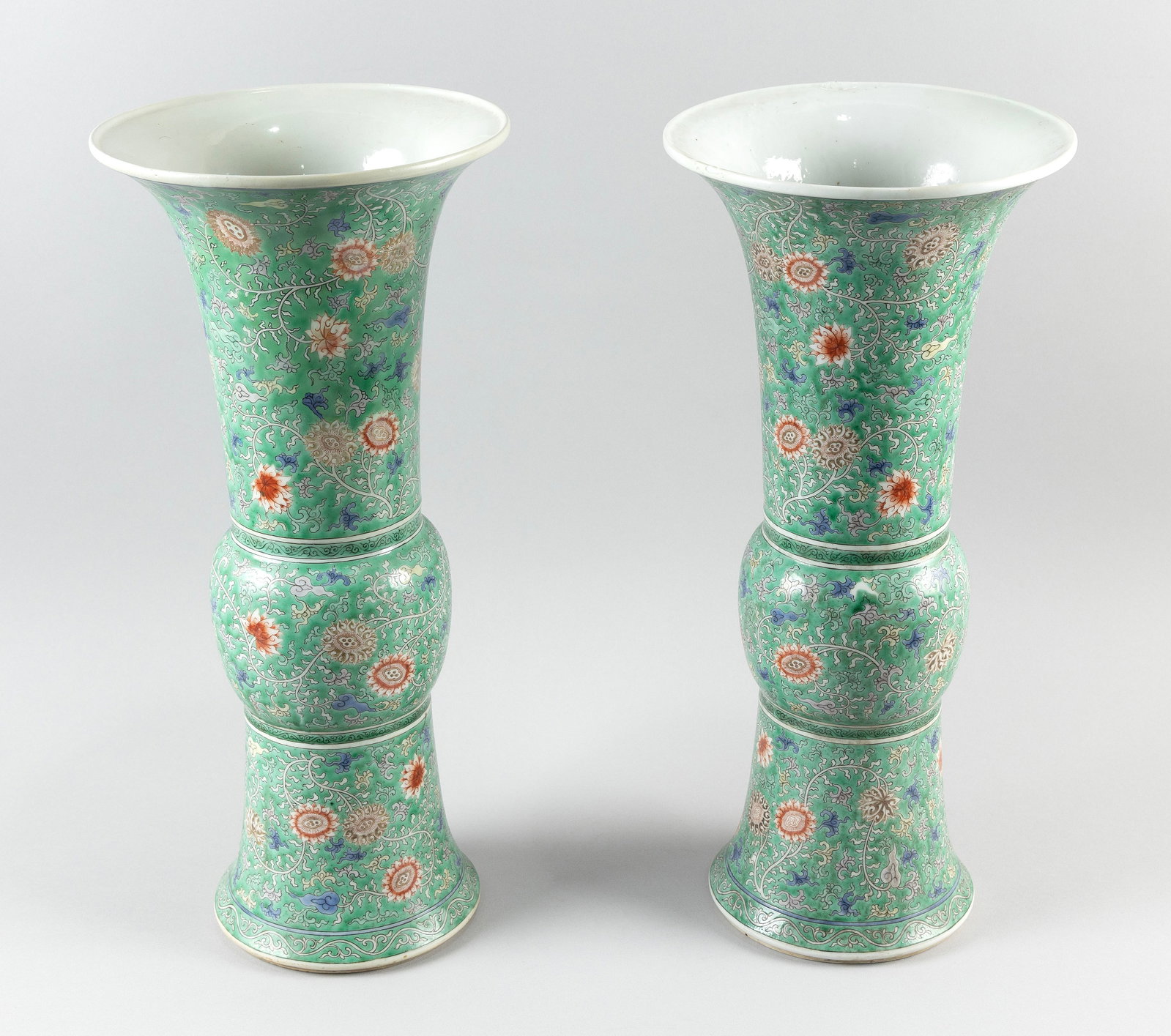 PAIR OF CHINESE FAMILLE ROSE PORCELAIN GU-FORM VASES 19th Century Heights 19". Diameters at mouth: PAIR OF CHINESE FAMILLE ROSE PORCELAIN GU-FORM VASES 19th Century With trumpet mouths and allover floral and vine decoration. Six-character Kangxi mark on bases. Heights 19". Diameters at mouth 9". Pr