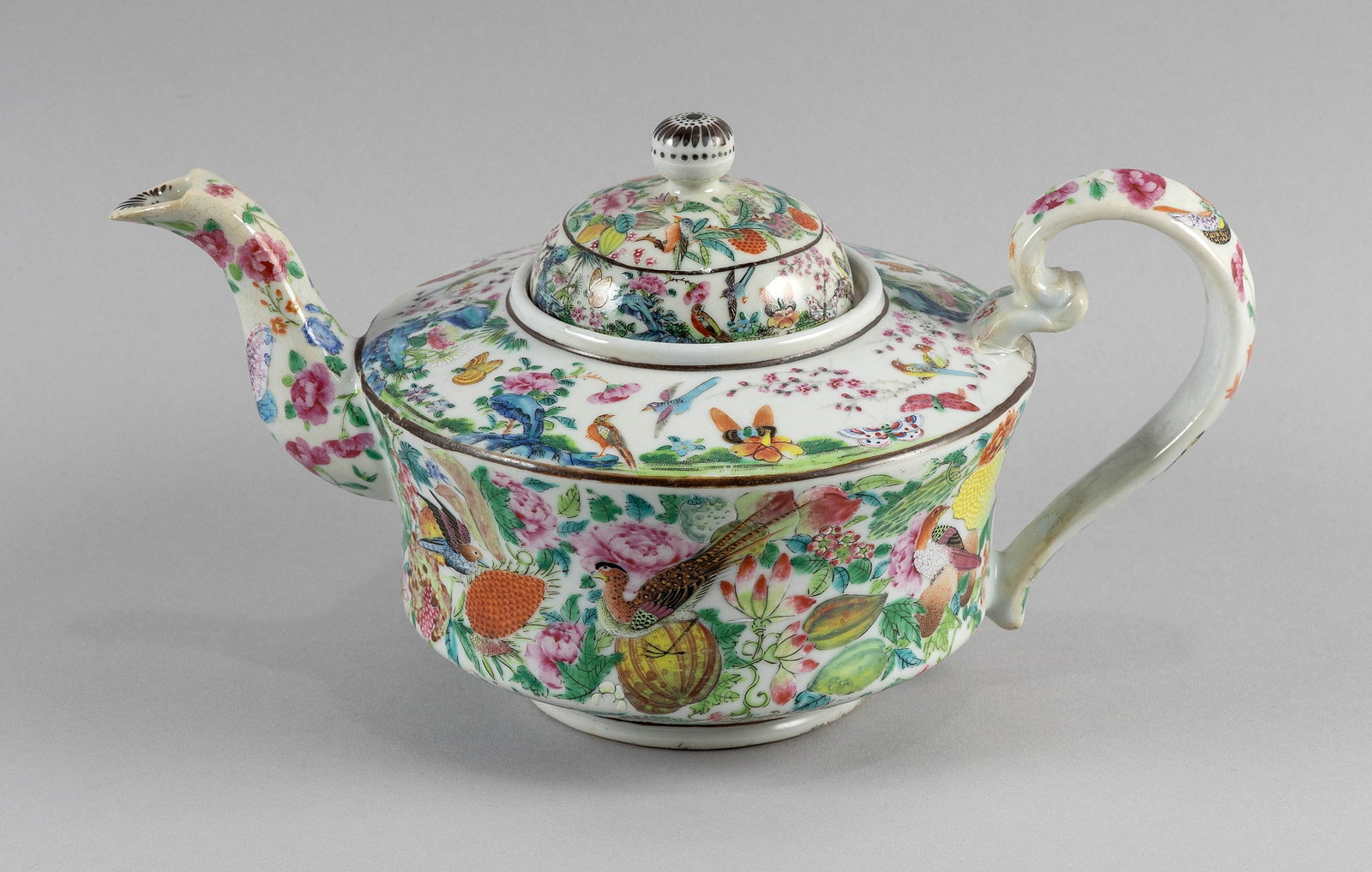 CHINESE EXPORT FAMILLE ROSE PORCELAIN TEAPOT Late 19th Century Height 6.5". Length 11".: CHINESE EXPORT FAMILLE ROSE PORCELAIN TEAPOT Late 19th Century Decoration of birds and butterflies in a floral and rockery landscape about the body. Conforming domed cover with a black-painted chrysan