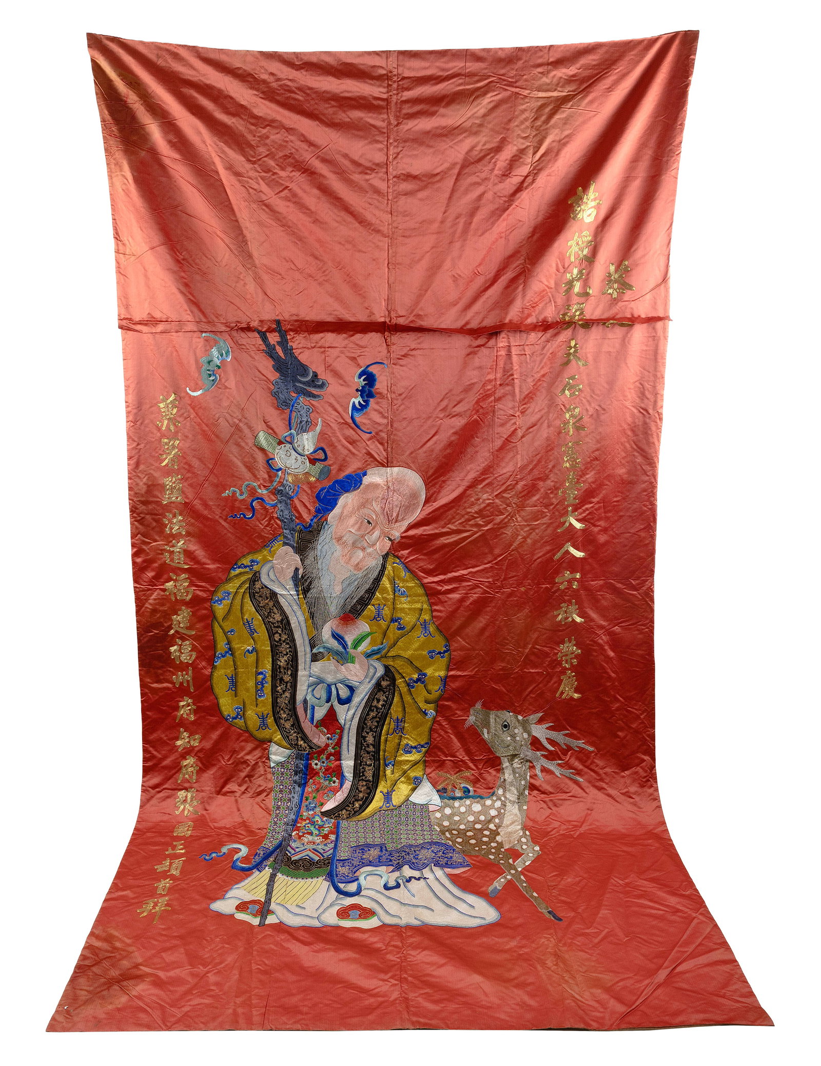 CHINESE OVERSIZED SILK EMBROIDERED PANEL Late 19th/Early 20th Century 113" x 58".: CHINESE OVERSIZED SILK EMBROIDERED PANEL Late 19th/Early 20th Century Depicts Shou Xing holding a peach and a staff and looking down upon a spotted deer. Colorful bats above, and gold calligraphy at l