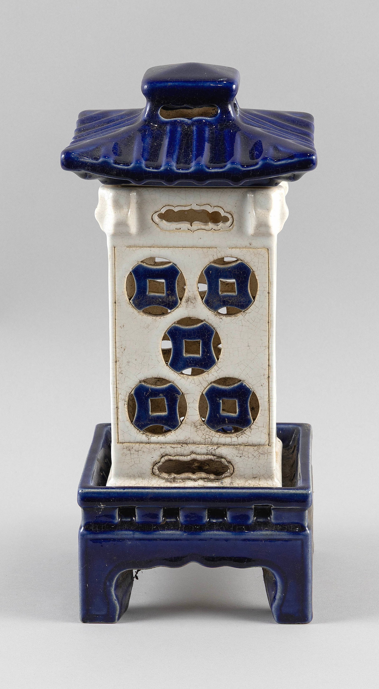 CHINESE BLUE AND WHITE PORCELAIN THREE-PIECE LANTERN Late 19th Century Height 14". Length 6". Width: CHINESE BLUE AND WHITE PORCELAIN THREE-PIECE LANTERN Late 19th Century White square body with blue glaze cut-out coin decoration. Blue roof-form cover and four-footed base. Height 14". Length 6". Widt