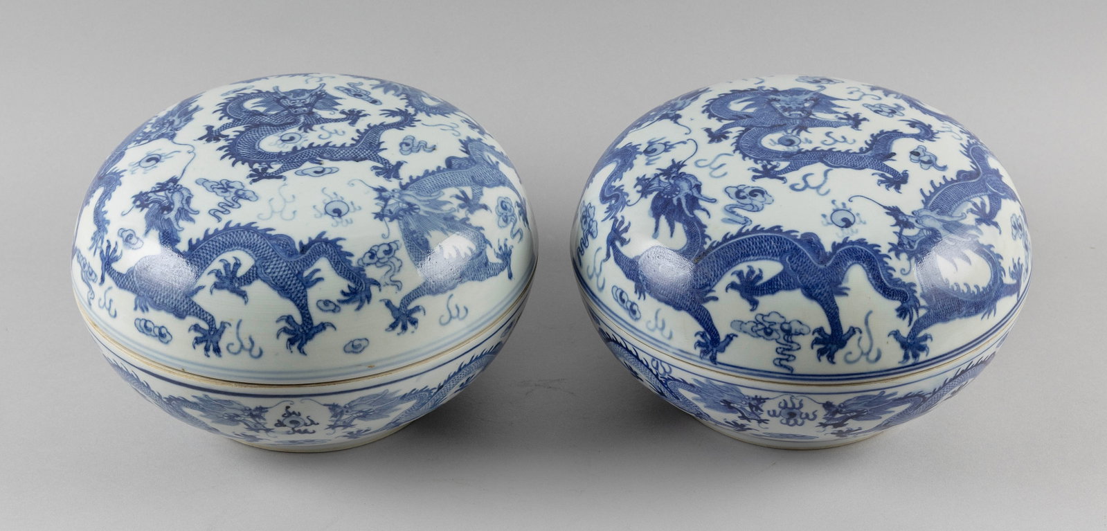 PAIR OF CHINESE BLUE AND WHITE PORCELAIN COVERED DRAGON BOWLS Early 20th Century Heights 7".: PAIR OF CHINESE BLUE AND WHITE PORCELAIN COVERED DRAGON BOWLS Early 20th Century Five-clawed dragon, pearls and cloud decoration. Six-character Guangxu mark on bases. Heights 7". Diameters 10".