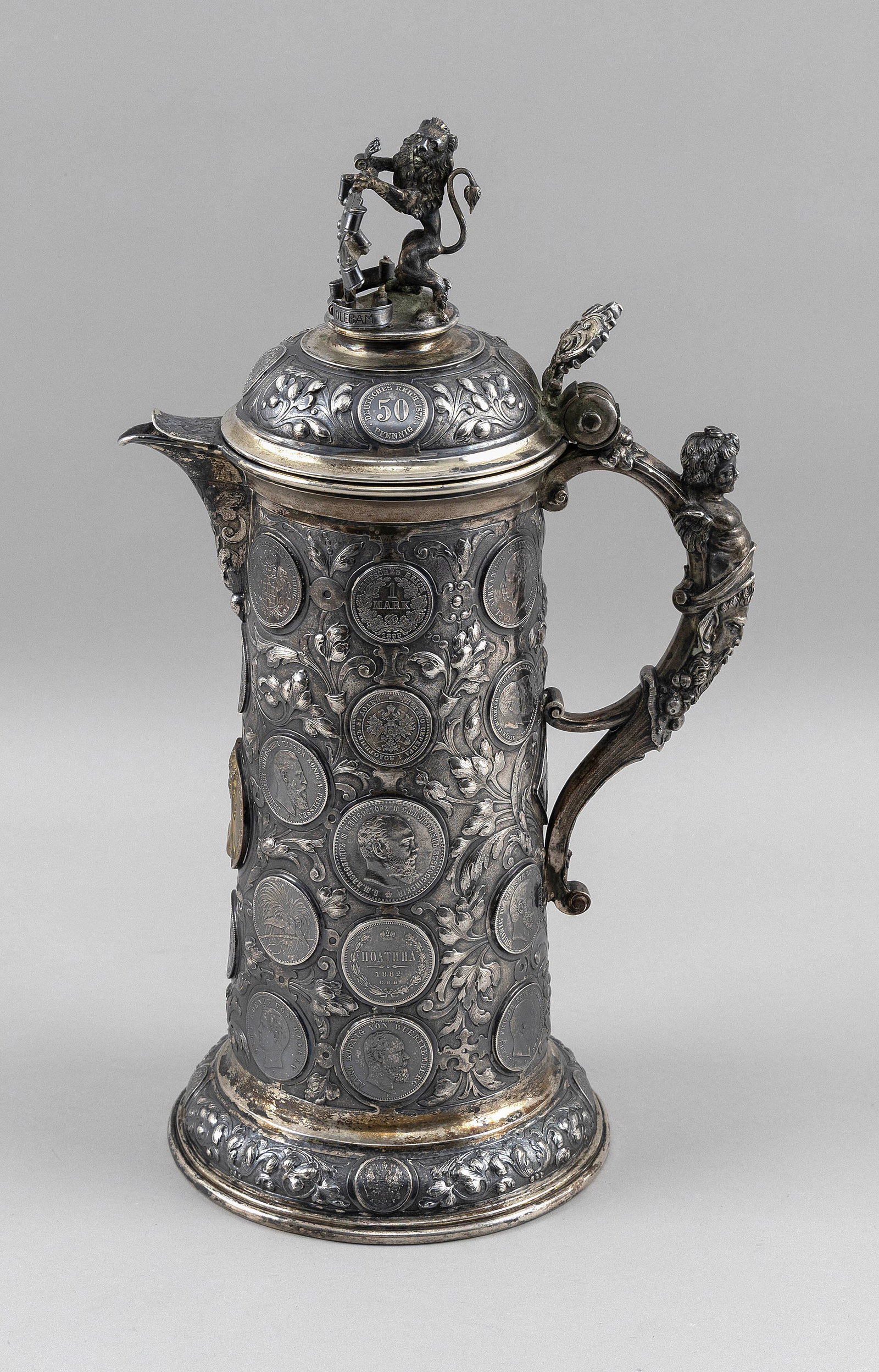 CONTINENTAL 800 SILVER COIN TANKARD Late 19th Century Approx. 40.0 troy oz.: CONTINENTAL 800 SILVER COIN TANKARD Late 19th Century Wonderful repoussE and hand-chased floral and swag design surrounds inset coins dating from the 1880s and 1890s. Figural handle with a cherub atop