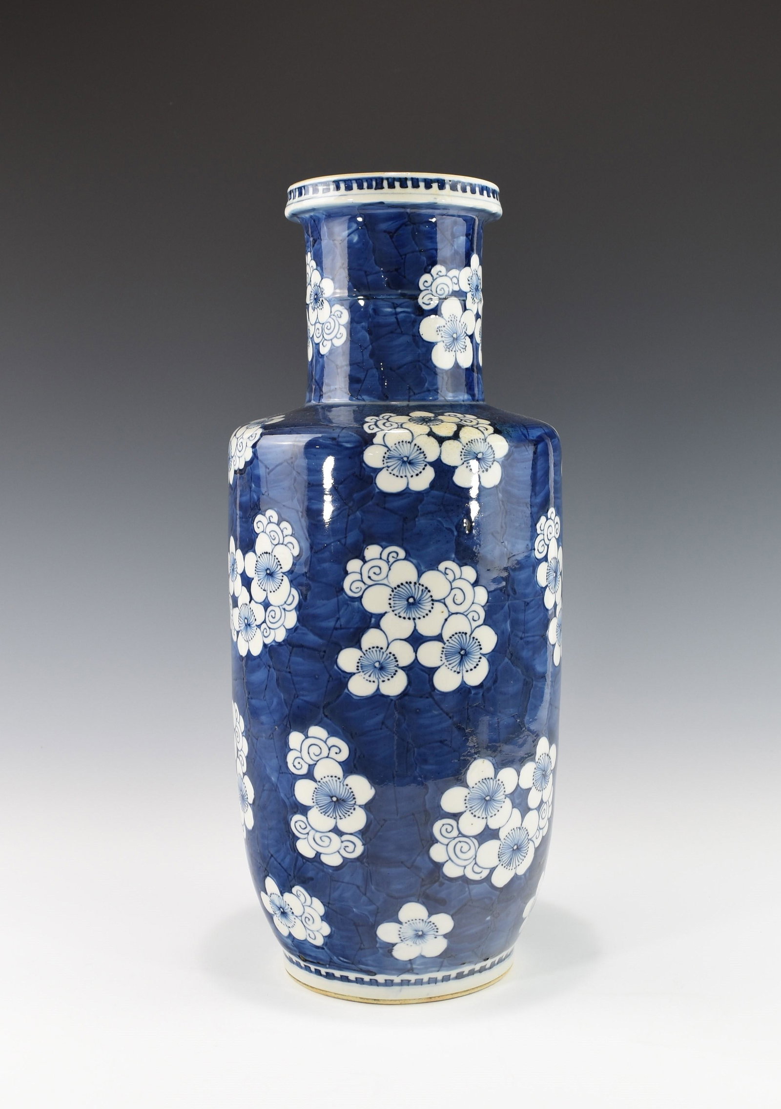 A CHINESE BLUE AND WHITE ROULEAU VASE, 19TH CENTURY: Decorated with big prunus mume on a cobalt blue ice-crackled ground. Condition: some minor firing defects near the foot, such as air bobble bursts. Height: 17 ½ inches, 44.5 cm.