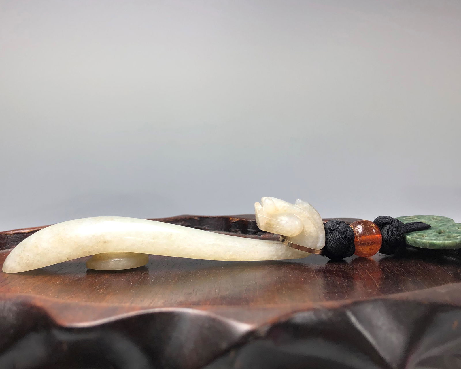 A 19TH CENTURY CHINESE JADE DRAGON BELT HOOK: With yellow gold clasp, an antique amber bead and a spinach jade openwork disc. Stand not included. Belt Hook 14 CM long, Total 14 CM long, Wt 33.7 gm