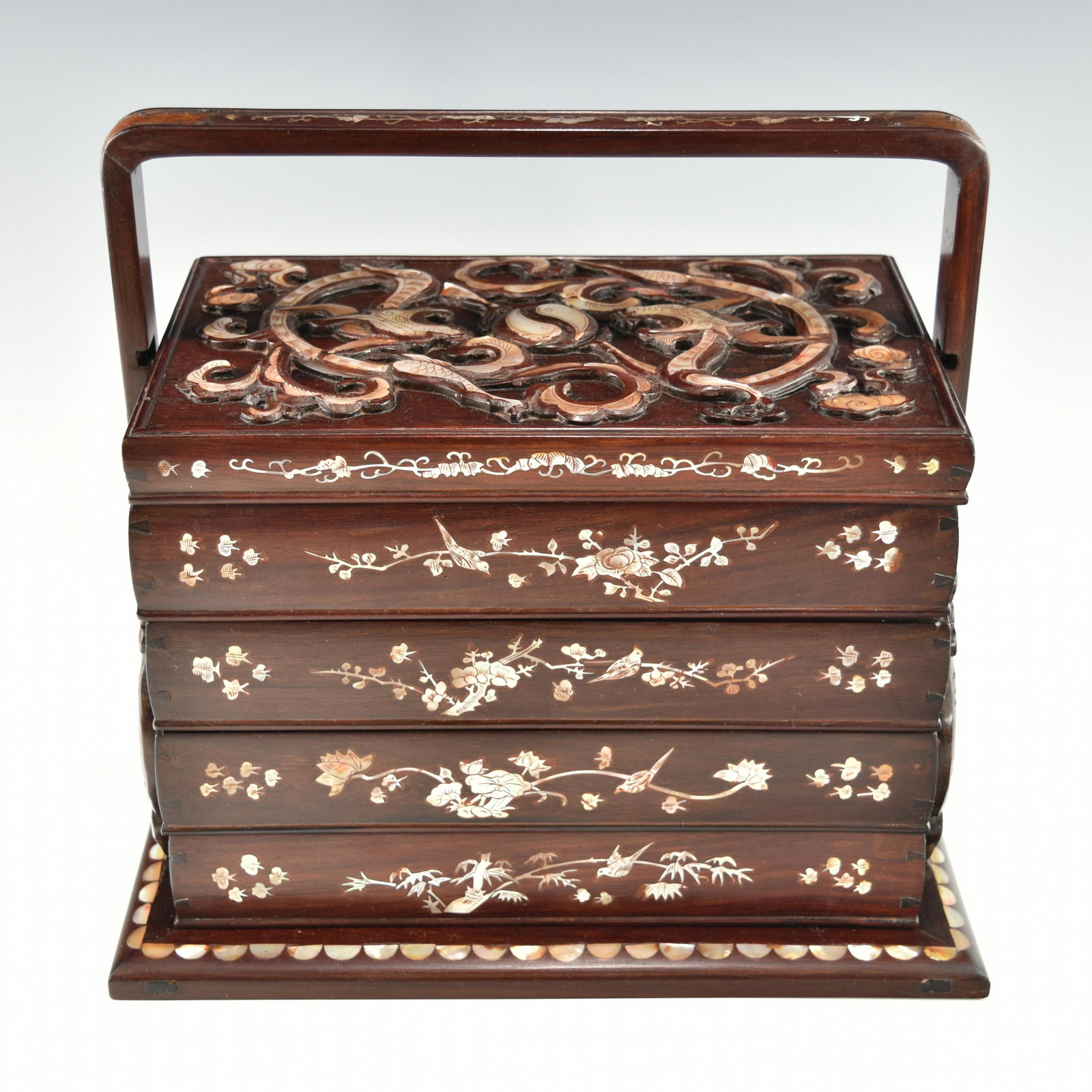 A CHINESE HARDWOOD 4-TIER BOX WITH MOTHER OF PEARL INLAY: Circa 19/20TH. On top of the lid and in high relief, are two dragons, a Yingyang fish medallion and stylized clouds. Very well made and beautifully decorated rare piece. Some wood shrinkage observed c