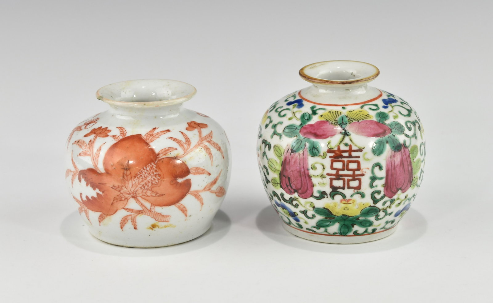 TWO CHINESE QING DYNASTY WATERPOTS: One decorated with iron-red auspicious fruits, bats and a longevity character, the other with vines, butterflies, auspicious fruits and two double happiness characters in famille rose enamel. The iron