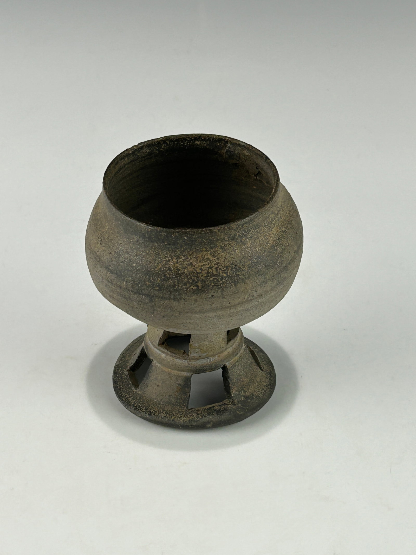 AN ANTIQUE KOREAN THREE KINGDOM PERIOD SILLA DYNASTY EARTHEN WARE PEDESTAL POT: With one restored area close to it mouth rim, otherwise in good vintage condition with signs of use and wear. Please refer to the photos for more details. Size: 8.3 cm x 8.3 cm x 10.5 cm 3-1/4"x 3-1/4