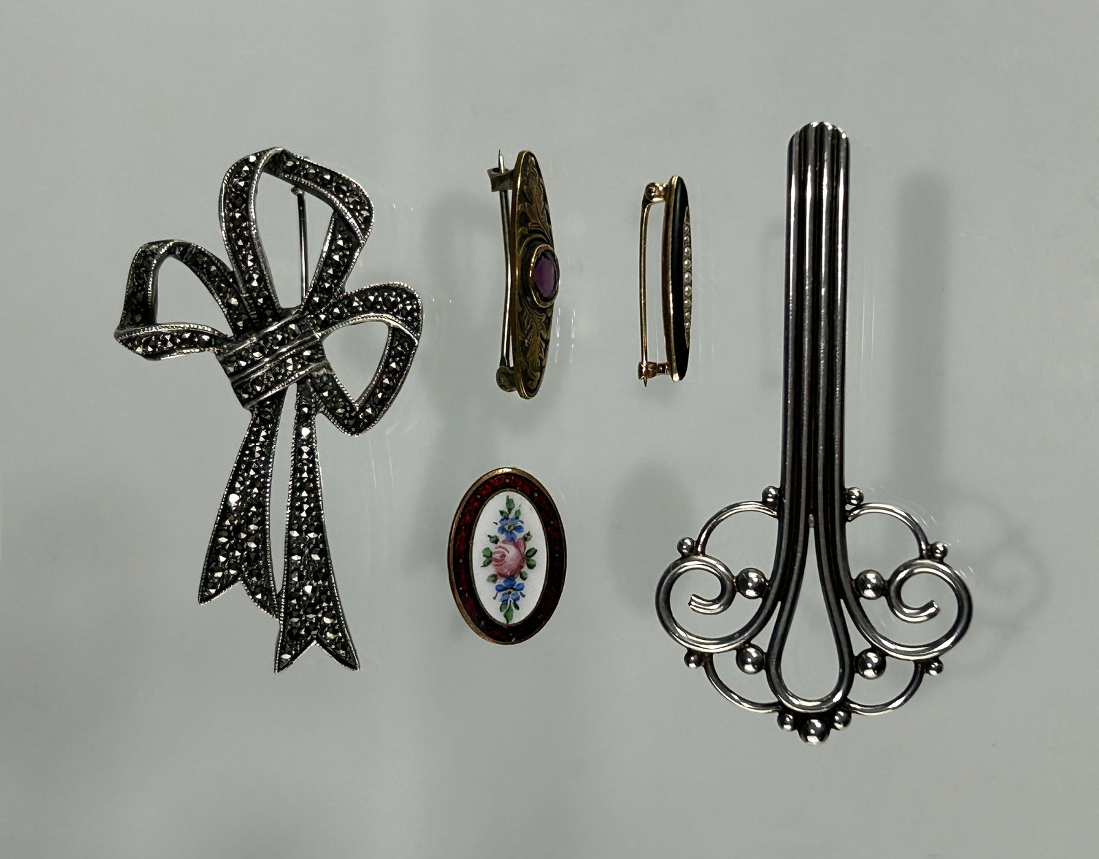 A GROUP OF ANTIQUE AND VINTAGE PINS WITH GOLD/SILVER/SEED PEARL: This collection reflects a range of styles from the late 19th to early 20th centuries, highlighting both ornate and minimalist trends in vintage jewelry design. Including: 1. Marcasite Bow Brooch, in 