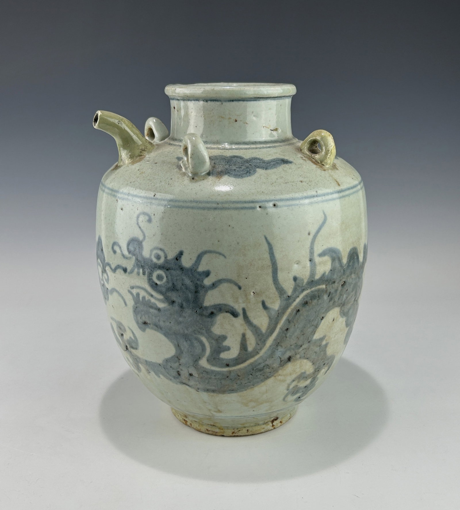 19TH CENTURY KOREAN BLUE AND WHITE DRAGON WINE VESSEL, JOSEON DYNASTY: Of globular form with short neck, spout, and four applied loop lugs around the shoulder, intended for suspending or securing, it features a underglaze stylized dragon encircling the body amid floating