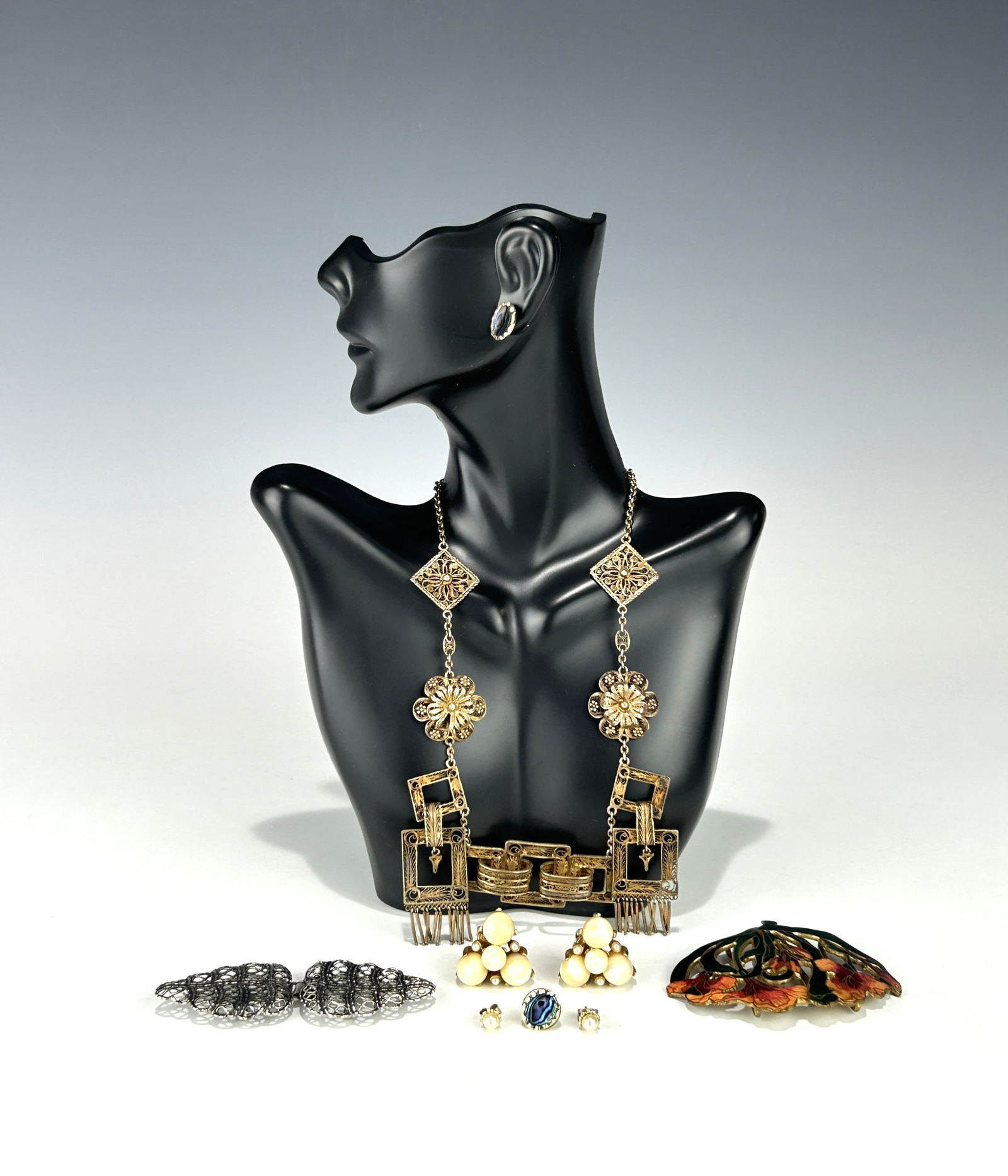 VINTAGE COSTUME JEWELRY LOT INCLUDING NECKLACE, BELT BUCKLE, AND EARRINGS: A varied lot of vintage costume jewelry featuring a range of materials, periods, and decorative styles: 1. Statement Necklace: An ornate necklace with square filigree links and floral medallions in a