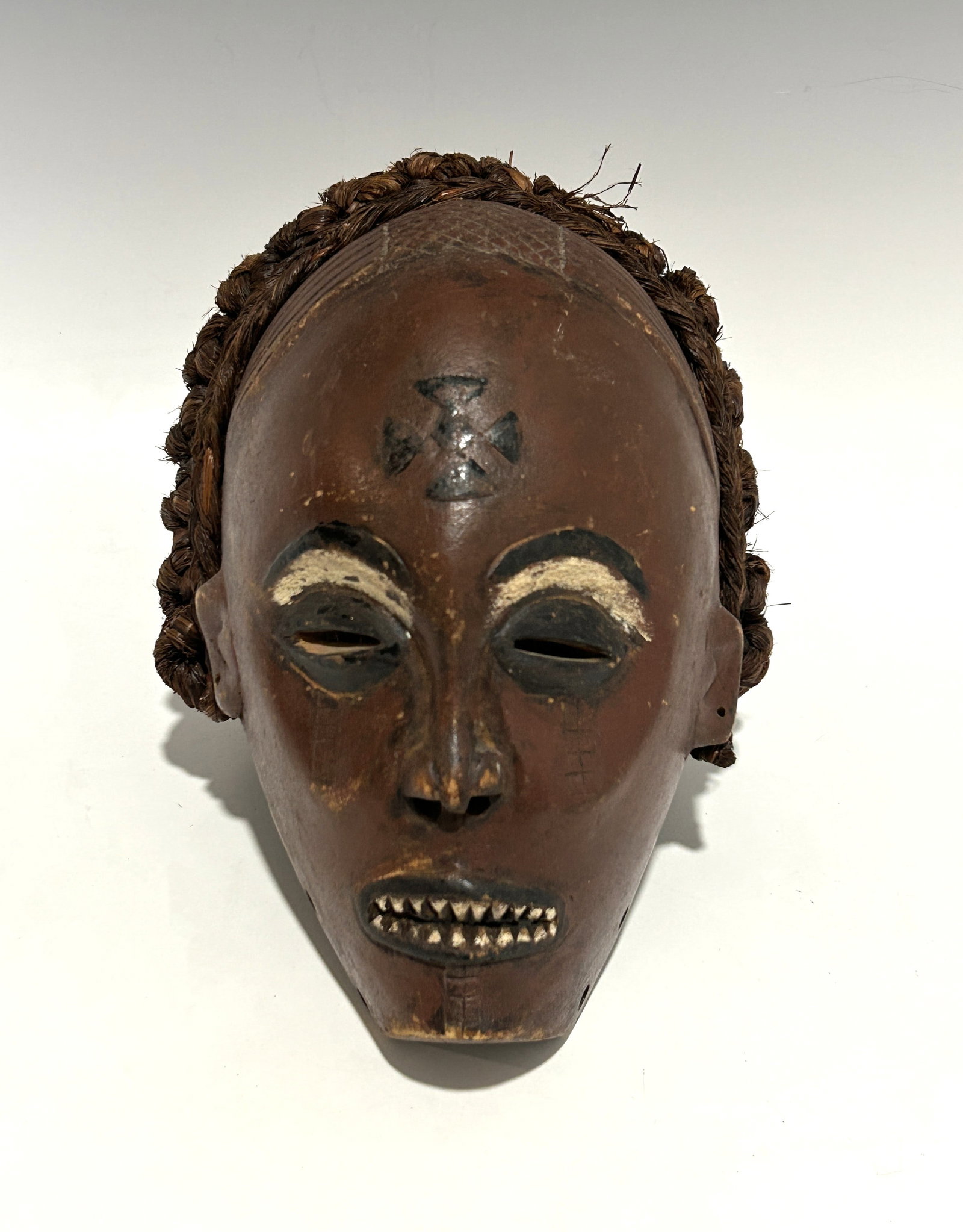 CHOKWE MASK, ANGOLA / DEMOCRATIC REPUBLIC OF THE CONGO, MID-20TH CENTURY OR EARLIER: An expressive hand-carved wooden mask attributed to the Chokwe people of Angola or the southern Congo region, dating to the mid-20th century or earlier. The mask features refined detailing and a warm 