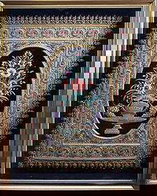 FRAMED ANTIQUE EMBROIDERED TAPESTRY LOADED WITH SEMI-PRECIOUS STONE INSETS: An elaborate framed embroidery on silk, worked in polychrome silk threads and metallic couched threads, depicting a central basket overflowing with stylized blossoms, framed within an oval border and