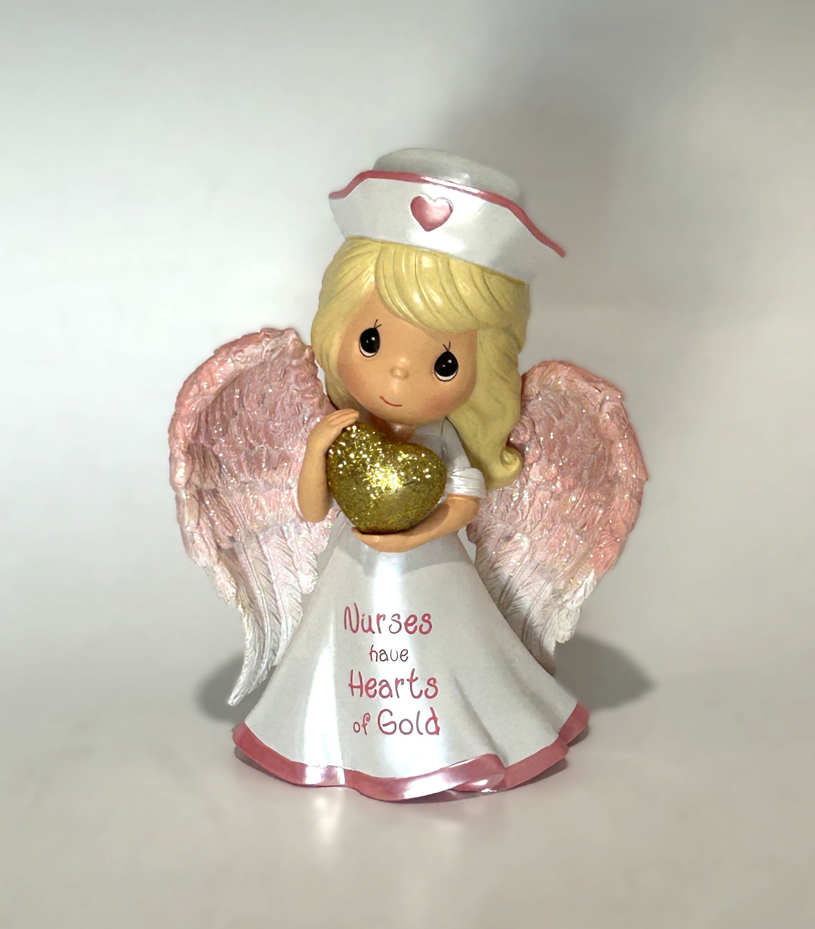 PRECIOUS MOMENTS “NURSES HAVE HEARTS OF GOLD?? FIGURINE: A limited edition Precious Moments porcelain bisque figurine titled “Nurses Have Hearts of Gold,” from the Nurses Are Heaven Sent collection. The piece depicts a sweet nurse angel with shimmer