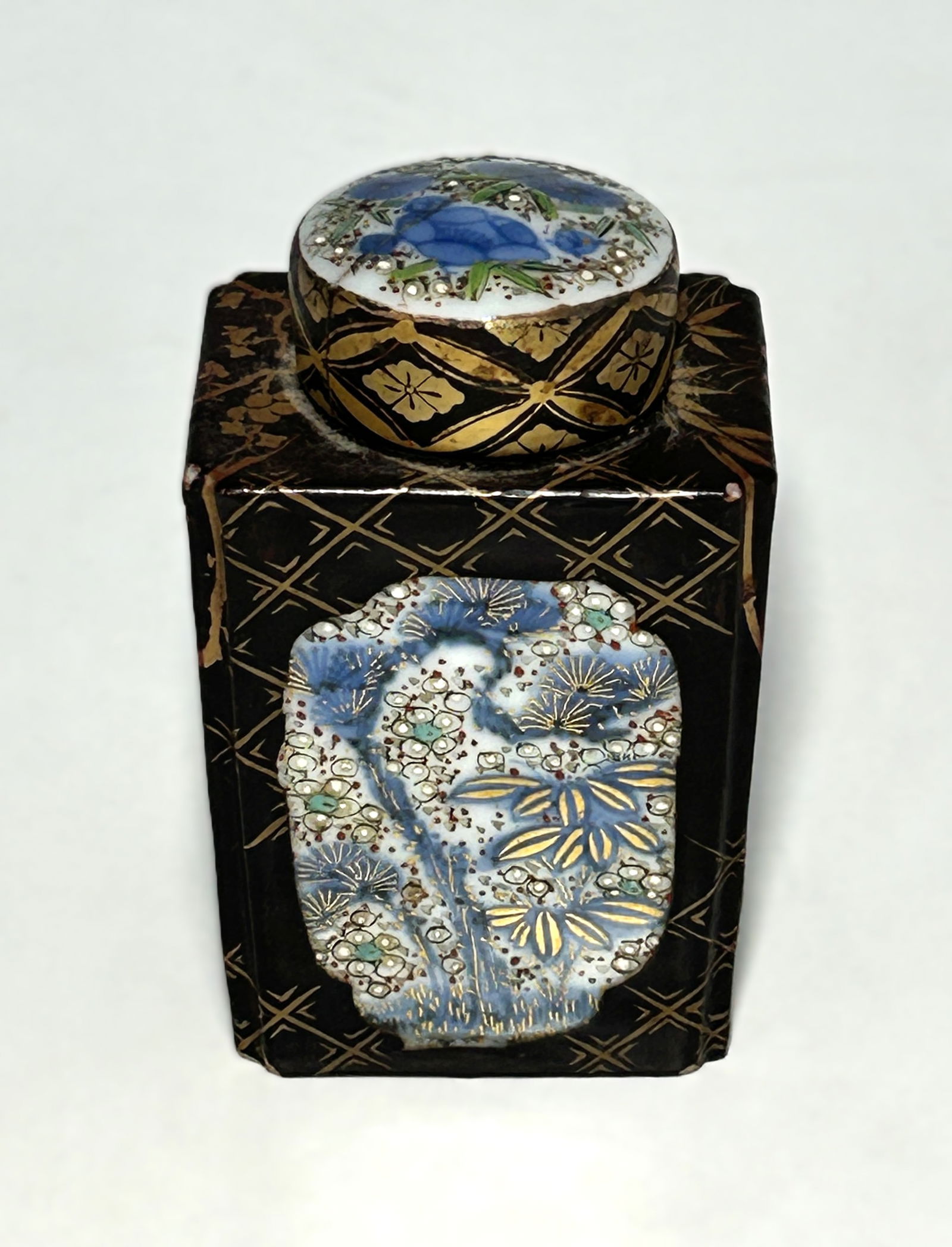 ANTIQUE JAPANESE MEIJI PERIOD SATSUMA TEA CADDY WITH COVER: Black ground with gilt floral and lattice decoration; inset enamel cartouches with blue and green floral motifs and moriage accents. White glazed interior. Meiji period (1868–1912). Condition consis