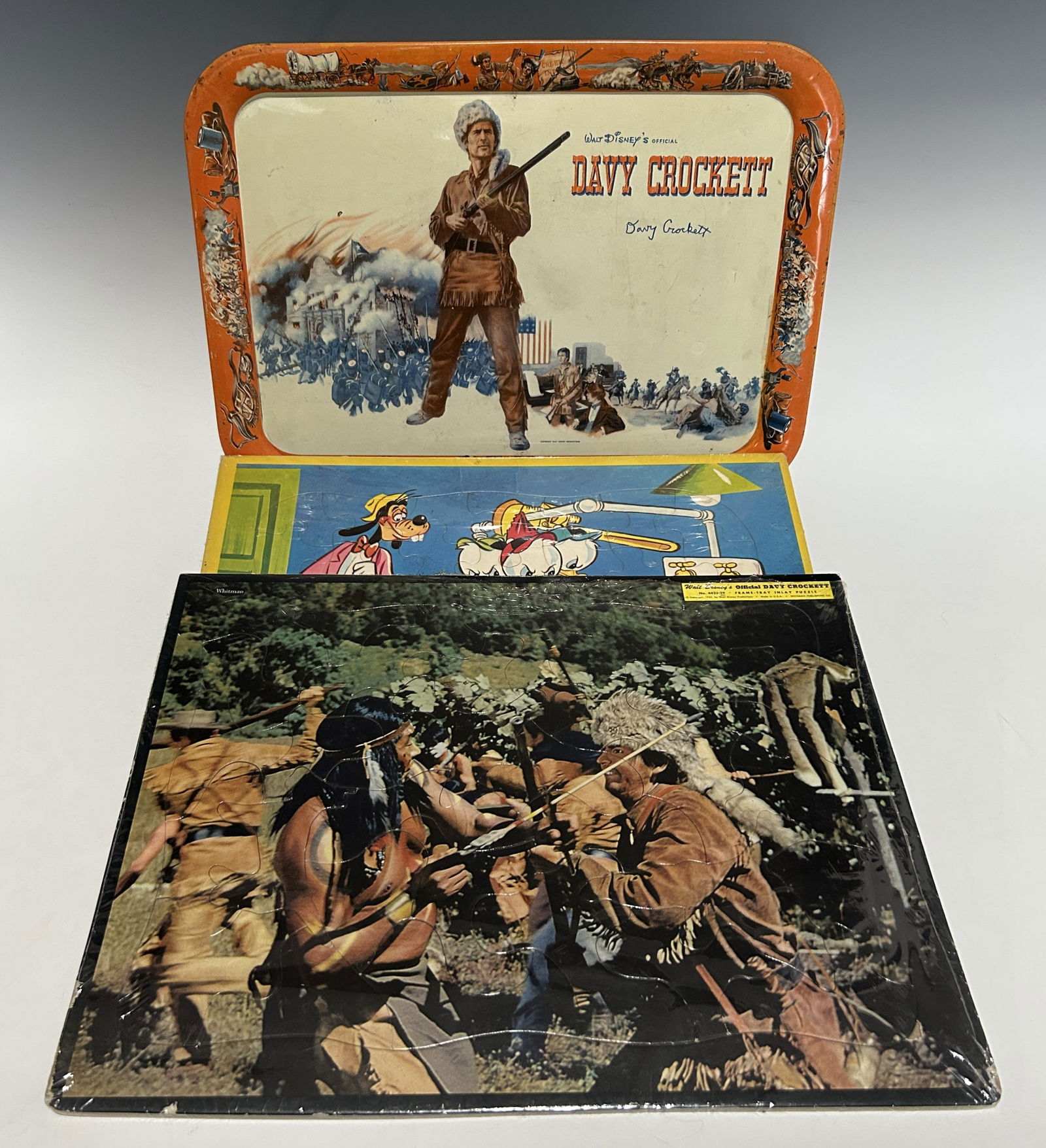 VINTAGE 1950'S WALT DISNEY DAVY CROCKETT SERVING TRAY WITH DAVY CROCKETT AND DONALD DUCK PUZZLES: Including . a vintage metal serving tray featuring imagery from Davy Crockett, depicting the frontiersman in buckskin attire against dramatic frontier battle scenes with an illustrated western-themed