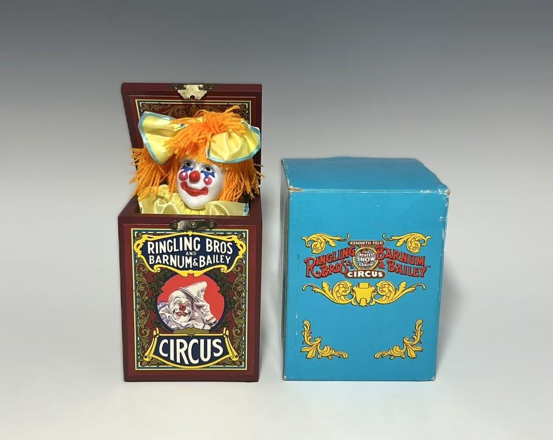 VINTAGE RINGLING BROS. AND BARNUM & BAILEY CIRCUS CLOWN JACK-IN-THE-BOX MUSIC BOX: Circus-themed collectible music box in the form of a jack-in-the-box with painted wooden case decorated with Ringling Bros. and Barnum & Bailey circus graphics and performer scenes. Hinged lid release