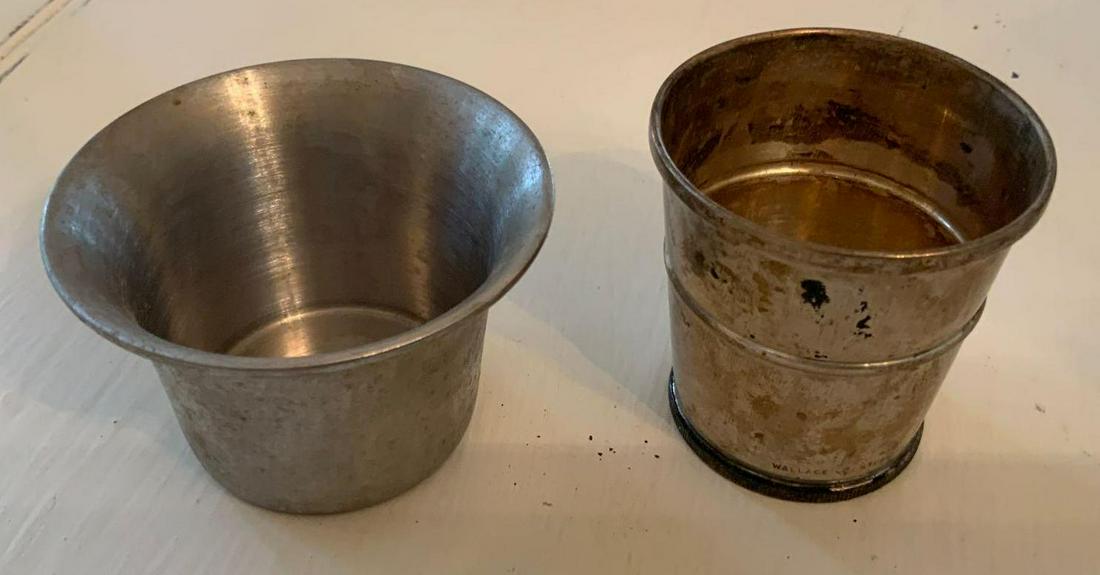 Two shot glasses, one stainless steel, one silver with: Two shot glasses, one stainless steel, one silver with coin on bottom, The silver one is a Wallace with the Wallace marking sterling number 5215 with a one dollar coin on bottom. Stainless is a vole p