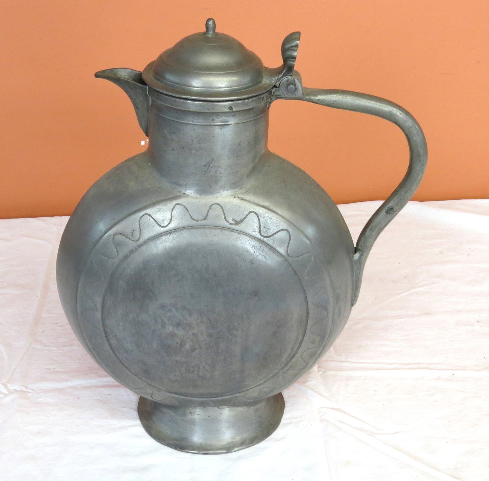 Pewter wine jug with lid and handle: Pewter wine jug with lid and handle, circular engraving on flat front, 14” h., x 9” diameter tank,