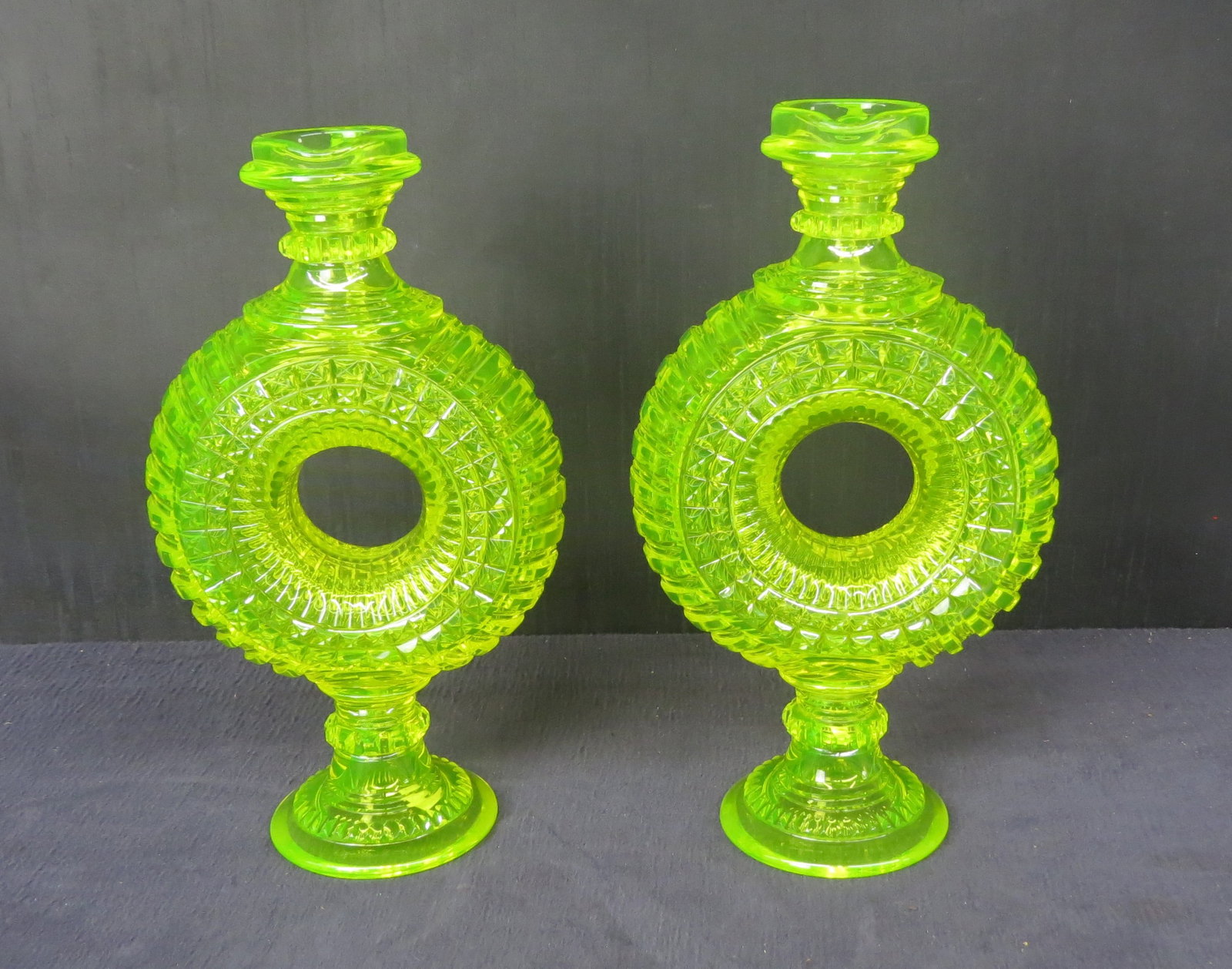 Pair Vaseline/uranium American Brilliant cut glass ewers: Pair Vaseline/uranium glass ewers, doughnut shaped body, block cut glass with applied handles, no chips or cracks, 12 ½” h. x 7” w.