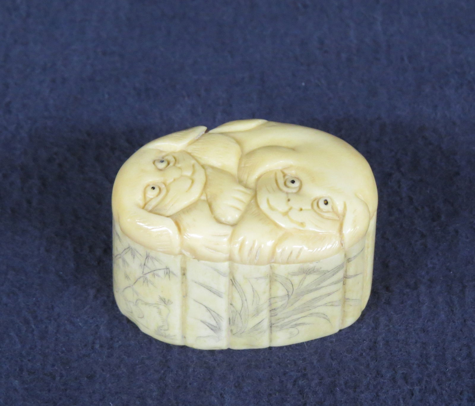 Small Oriental carved bone or tusk covered box: Small Oriental carved bone or tusk covered box, top has two carved dogs, sides have scrimshaw landscape with red ink signature, 1 1/4" h. x 2 1/4" w. good condition