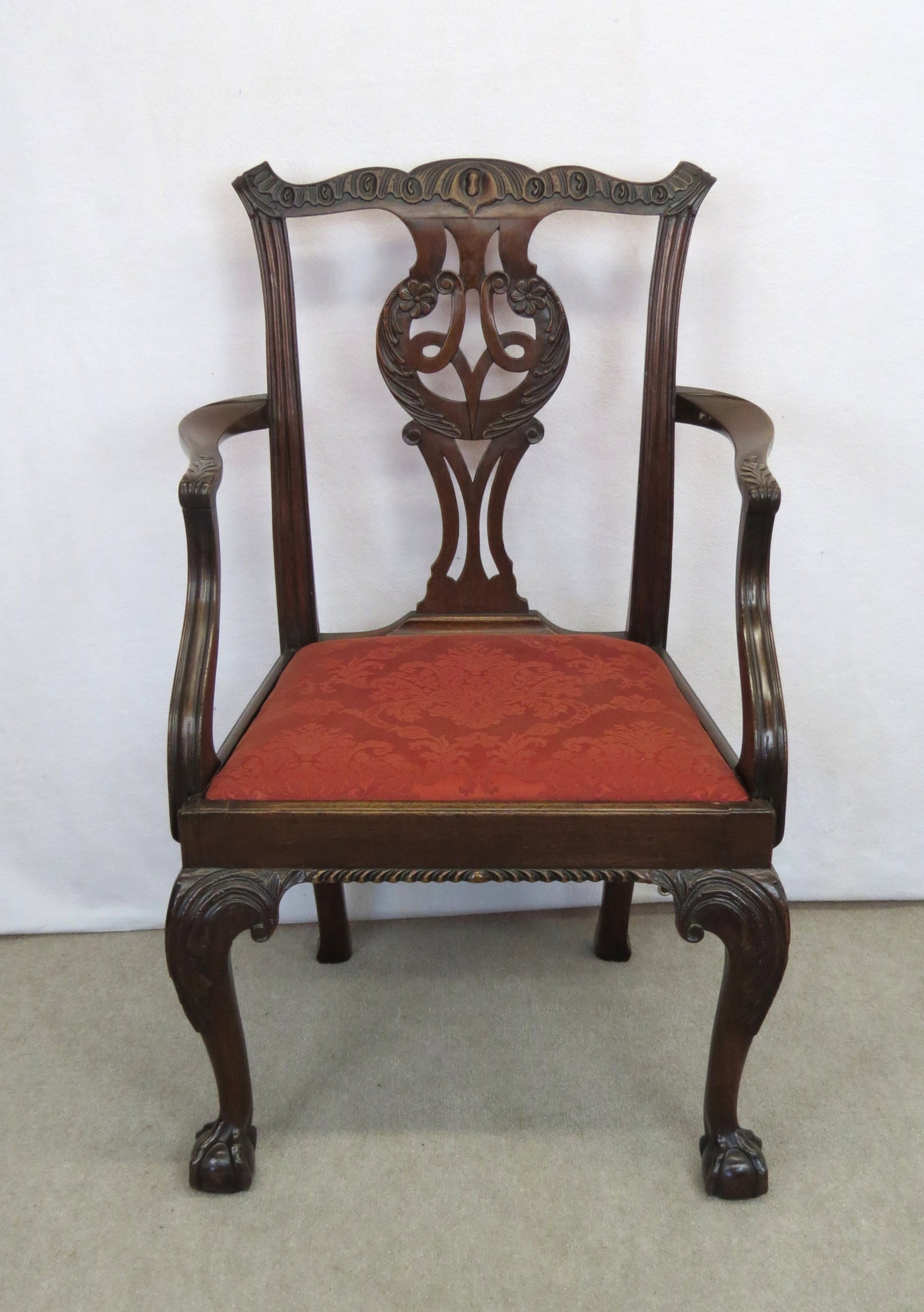 Carved mahogany claw and ball foot arm chair: Carved mahogany claw and ball foot arm chair, carved crest, carved splat with flowers, carved arms, knees and feet, dragoon carved skirt