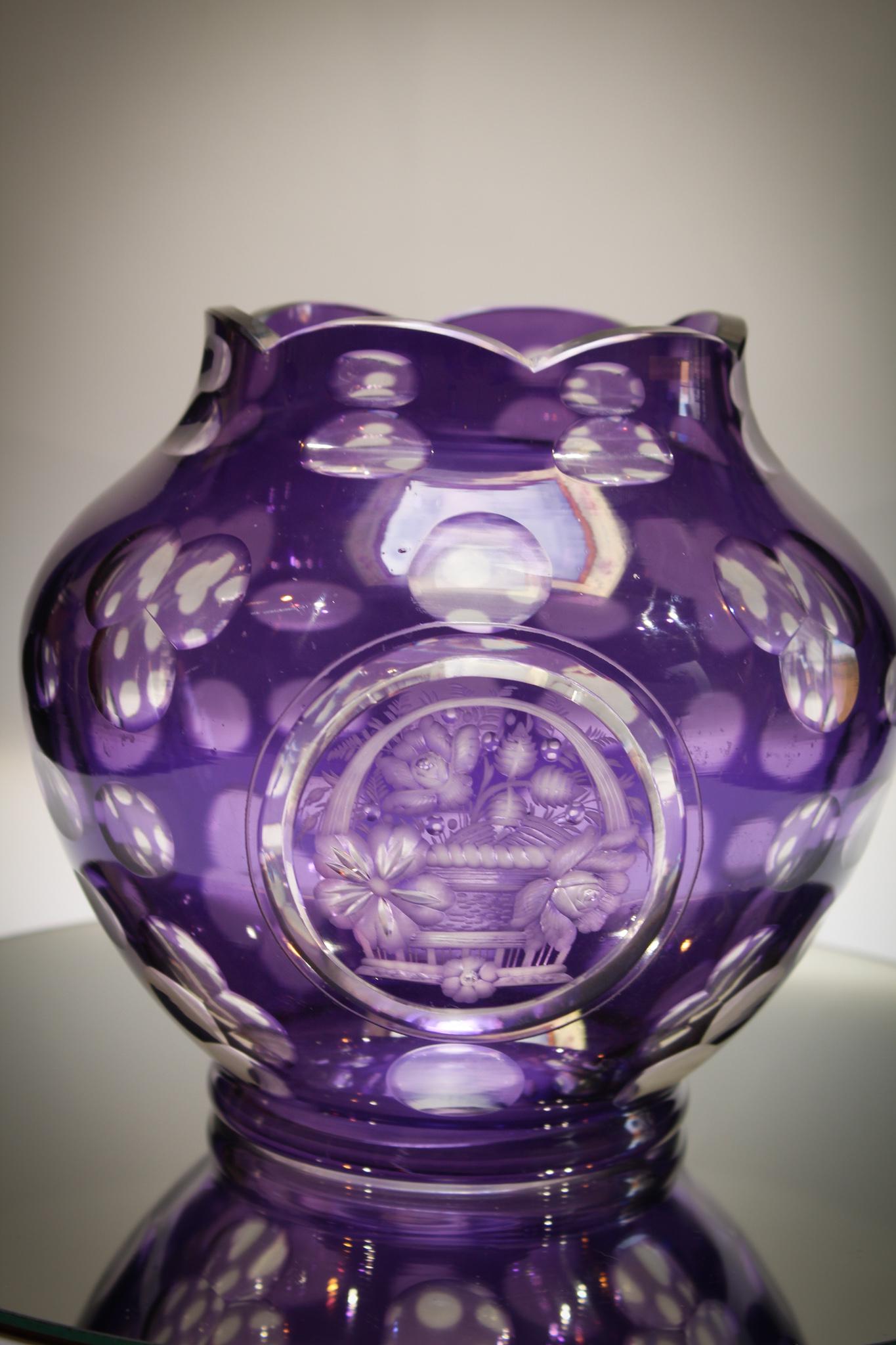 Amythest Cut to Clear engraved vase: Very showy vase in a beautiful amythest color. Pretty basket of flowers adorn the front side of the vase. Measures 7 1/2" tall, 8" wide.