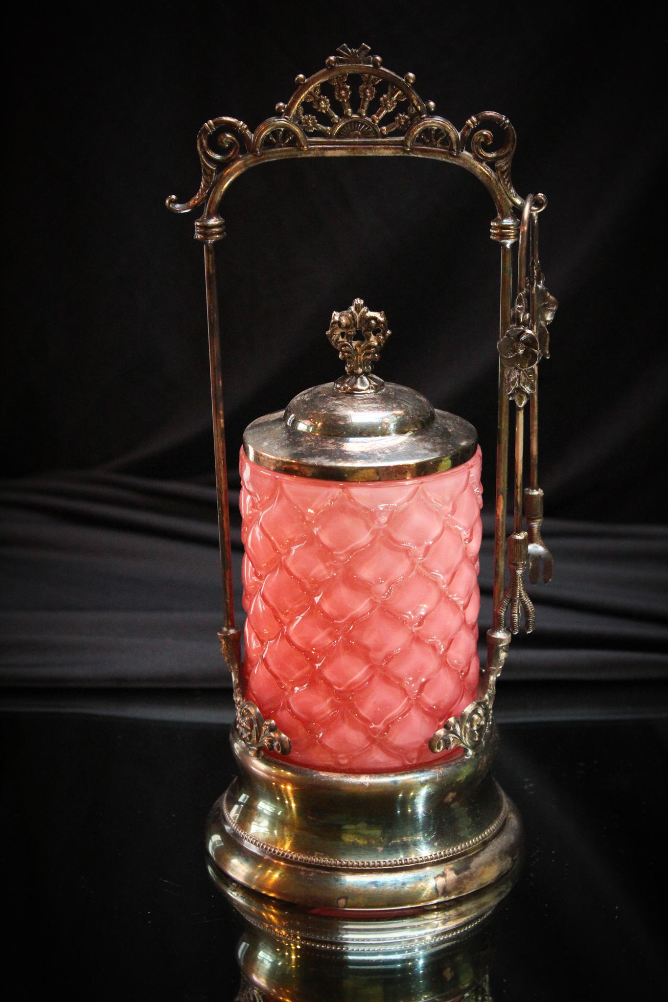 Forbes Consolidated Cone Victorian Pickle castor: Pretty in pink here folks. This Victorian pickle castor frame is signed Forbes Silverplate. Original jar is pink cased Consolidated glass Cone pattern. Complete with tongs. Measures 11" tall.