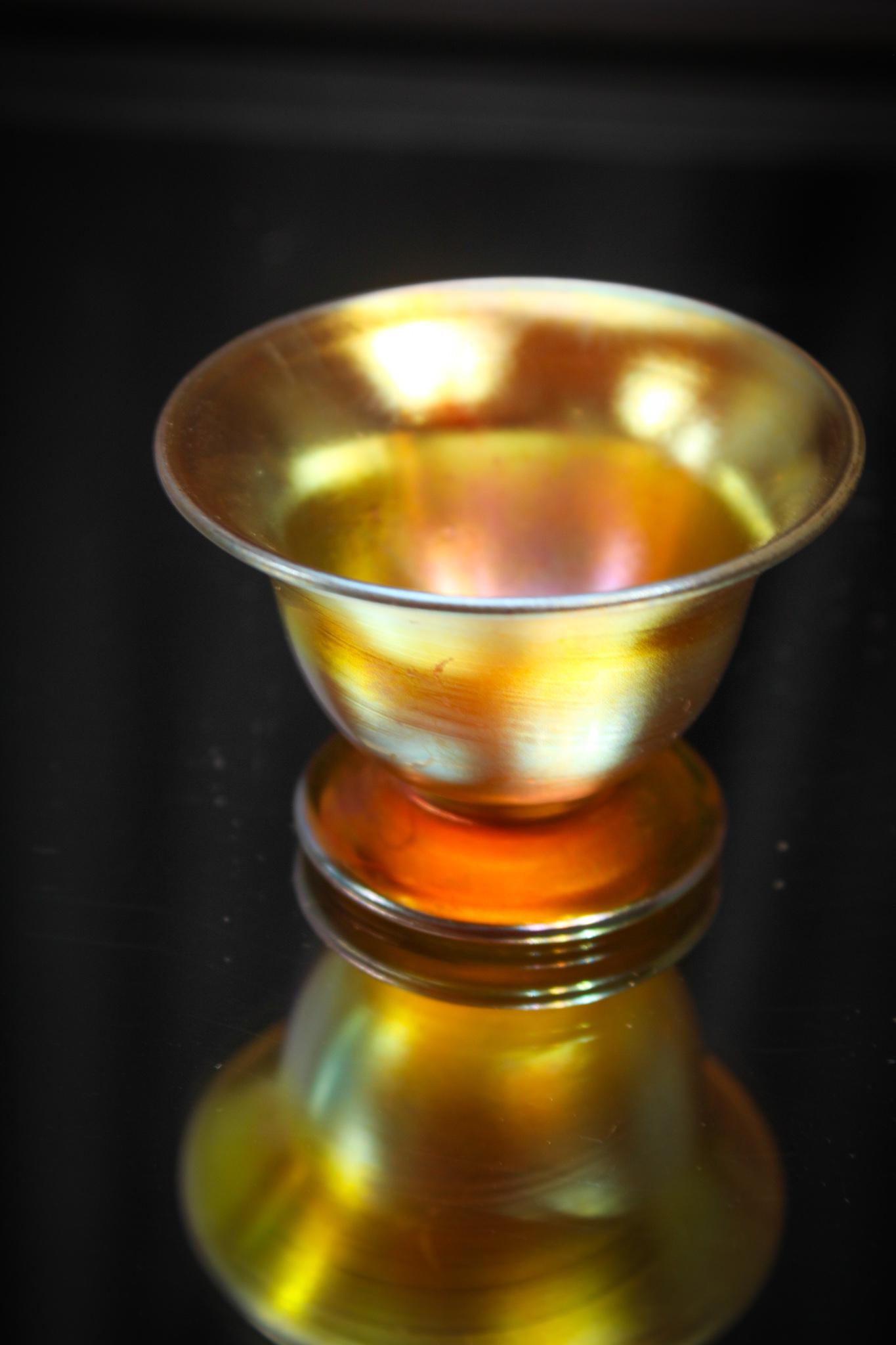 Steuben Gold Aurene pedestal open Salt: Can you imagine? I mean setting a table with these. Who on earth would have ever used these? Gold aurene pedestal open salt. Killer color. Measures 1 1/2" tall. Signed as shown.