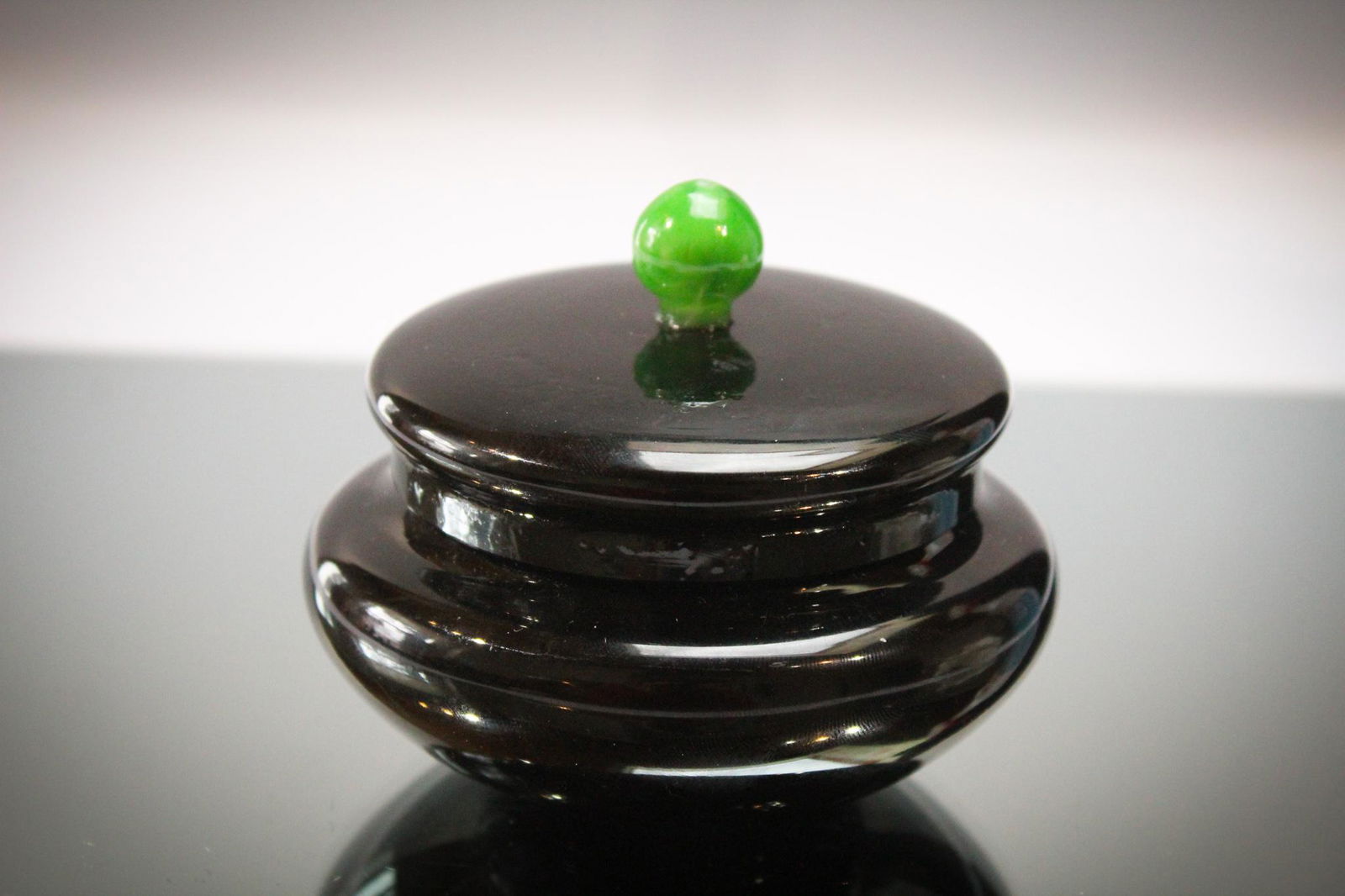 Attr. Steuben Glass Puff Box w/ Green Finial: Attributed to but not confirmed mirror black puff box with green finial. Measures 3" tall.