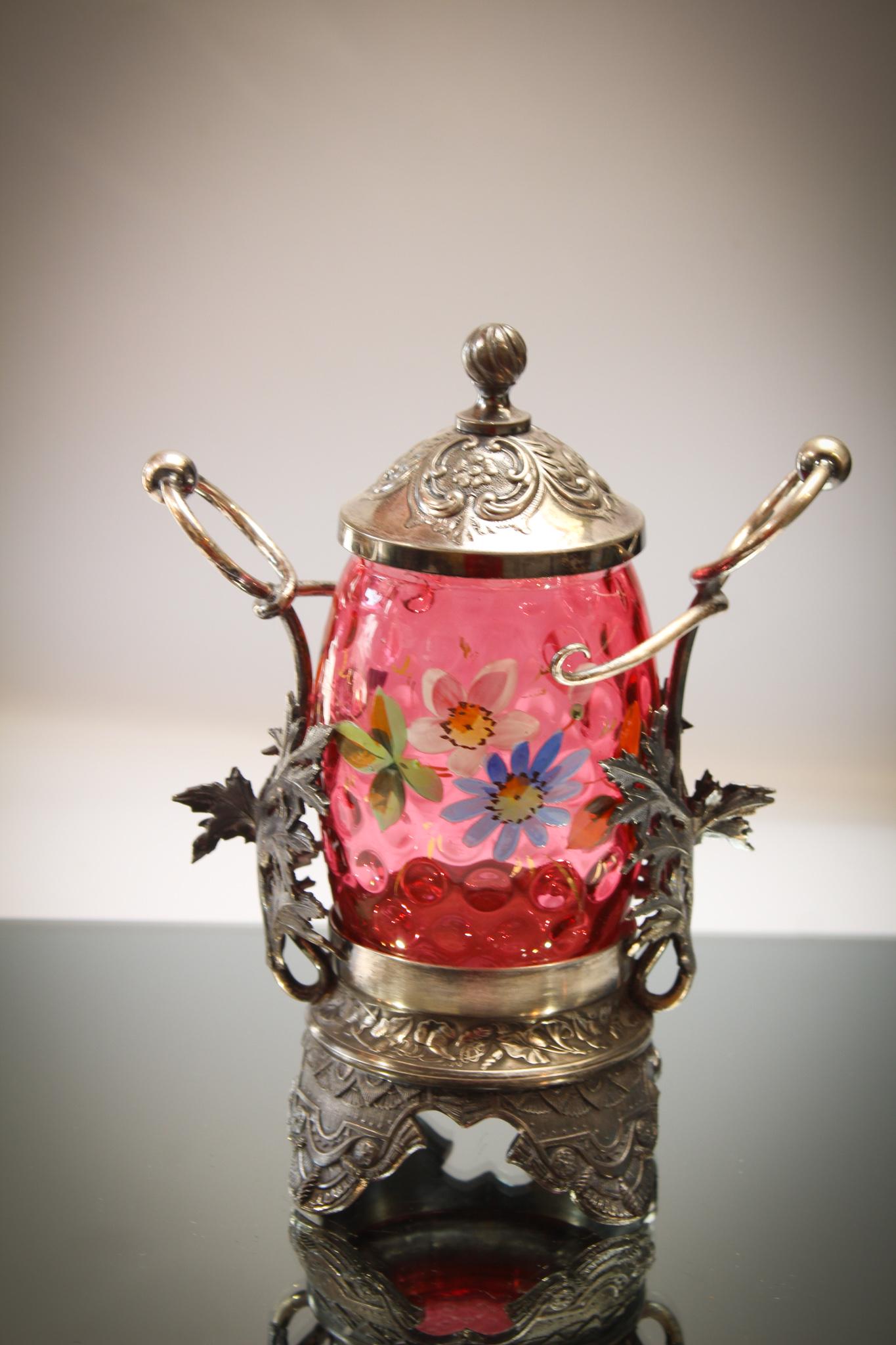 Wilcox Cranberry Enameled Glass Victorian Silverplate: A signed Wilcox Silverplate cranberry enameled pickle castor. Outstanding fabulous frame featuring leaves cradling the jar. Nice figural piece. Measures 9" tall.