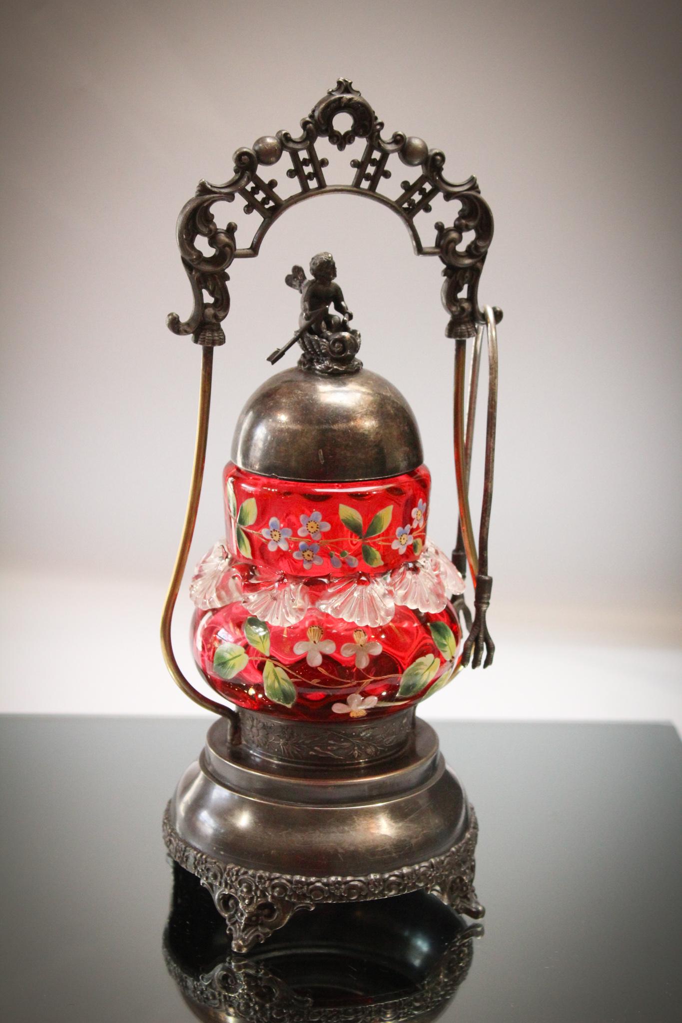 Toronto Silverplate Cherub Pickle Castor: Well Dahlings, this is a nice one. Cranberry enameled jar with applied clear glass rigaree set in a signed Toronto silverplate ornate frame. It is completed with a cherub riding in a leaf boat with ar