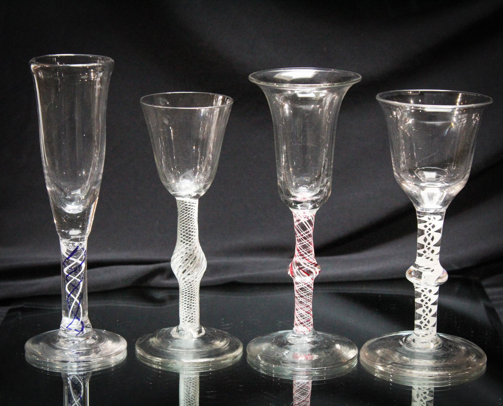 4 pc Lot 18th Century English Twist Stem Wine Glasses: Fabulous offering here folks. A four piece lot 18th century English wine stems. Beautifully made with double airtraps stems and ribbon glass stems. Mueseum stems. Tallest measures 7" tall.