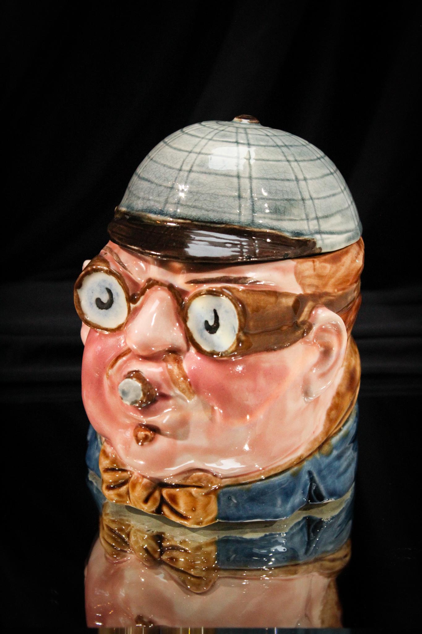 Victorian Majolica Humidor: What a charmer this one is! Man with racing goggles and a stogie in his mouth in Victorian majolica. Elaborate coloring to this one. Great piece. Measures 5 3/4" tall.