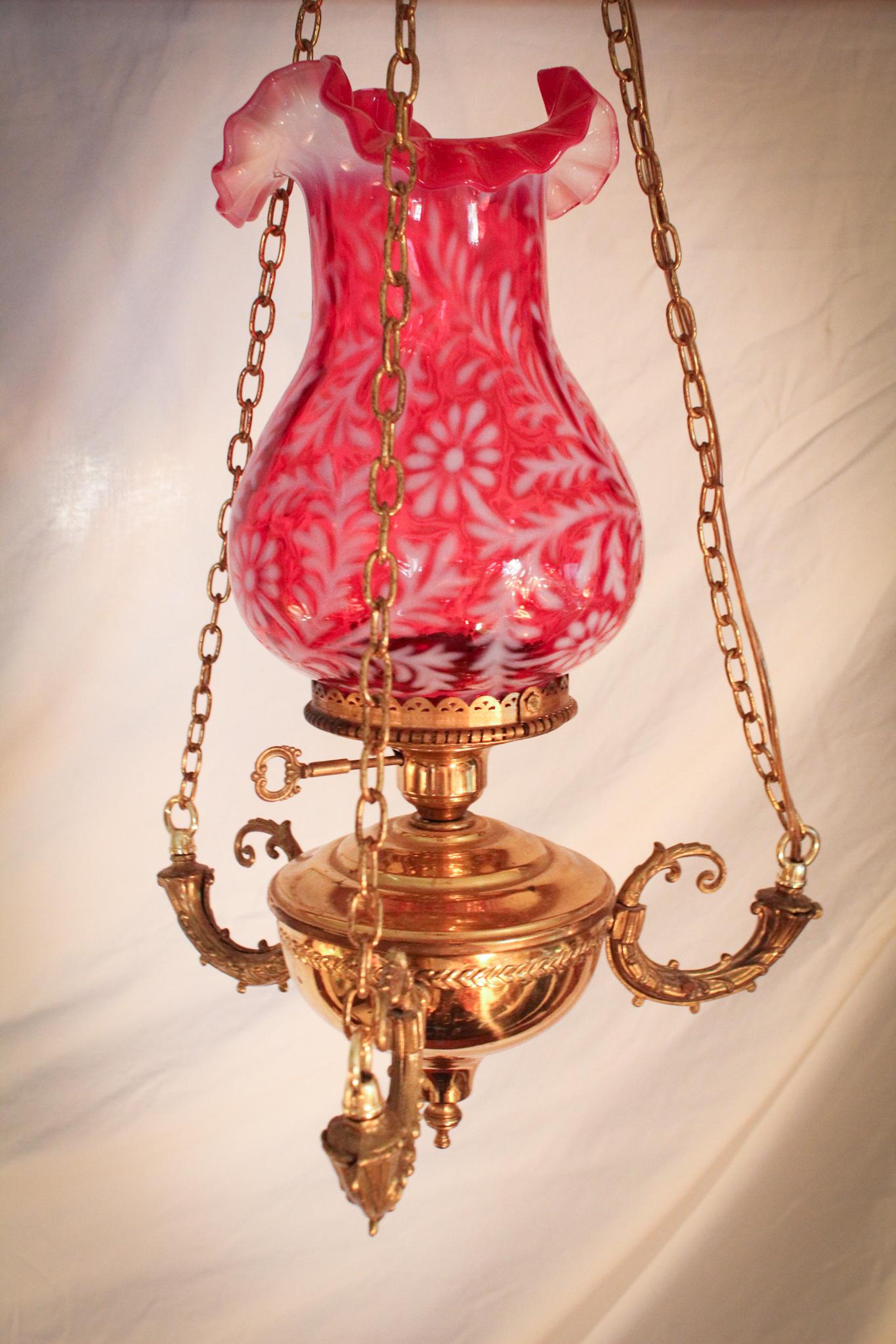 Fenton L.G. Wright Cranberry Opalescent Hanging Lamp: Very ornate brass hanging lamp complimented by a Fenton cranberry opalescent daisy and fern pattern tulip shade. This lamp is perfect compliment for anywhere. All you Fenton collectors out there stand