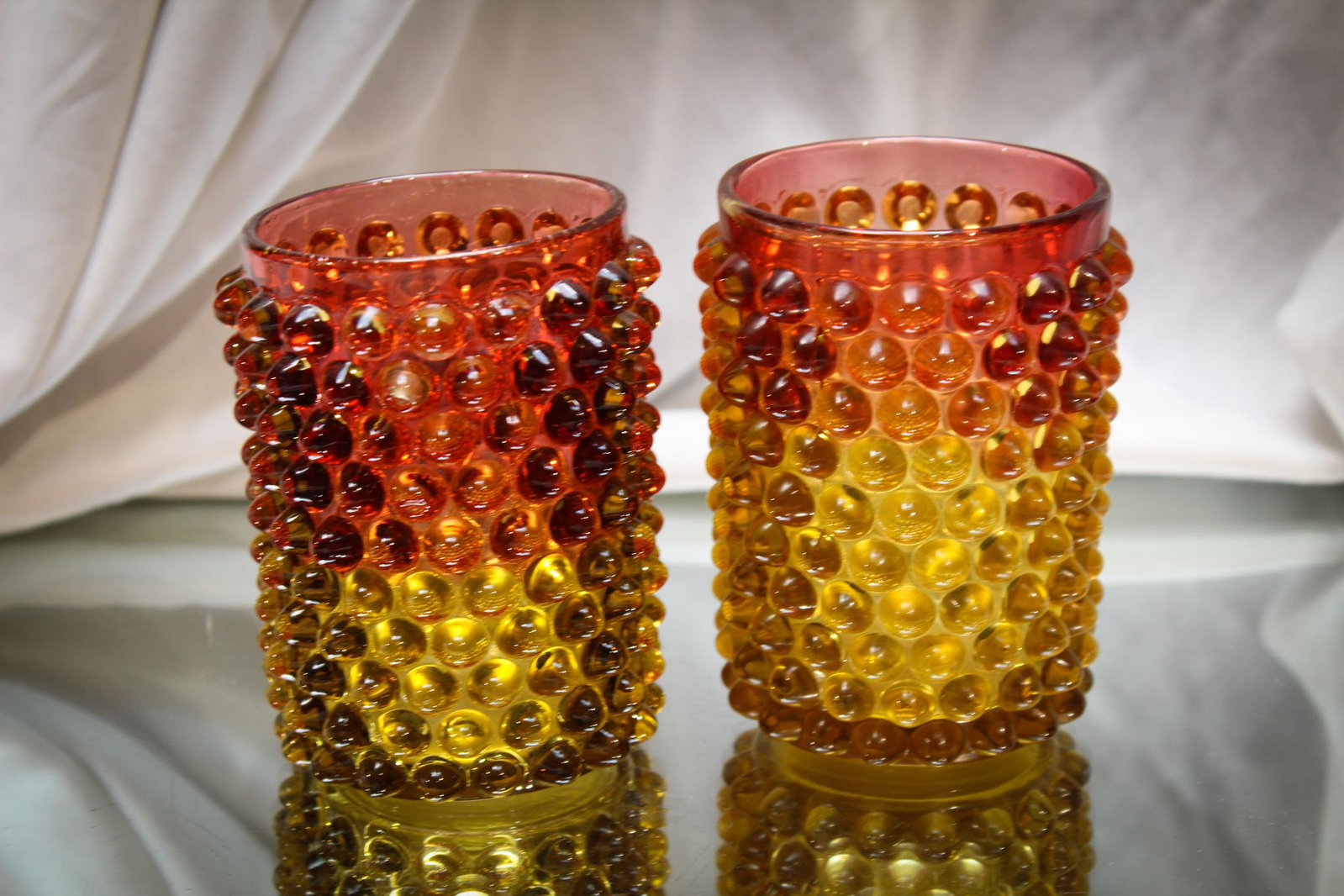 2 pc. Lot Hobb's Hobnail Victorian Amberina Glass Tumblers: We put these two guys together as they should be. Beautiful amberina coloring to these hobnail tumblers and well defined pattern. Always a favorite made by the Hobb's company. Each measures 4" tall.