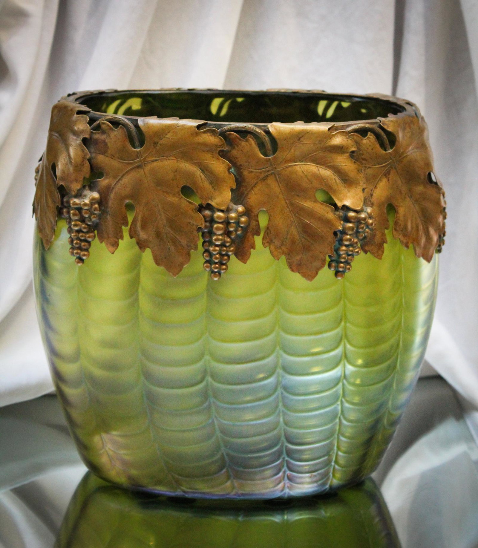 Bohemian Austrian Green with metal Grapes Collar Drapery vase: Excellent example of this form and pattern. Beautiful Austrian irridescent drapery vase in green with overlay collar of embossed grapes. Measures 9 1/2" by 9 1/2".