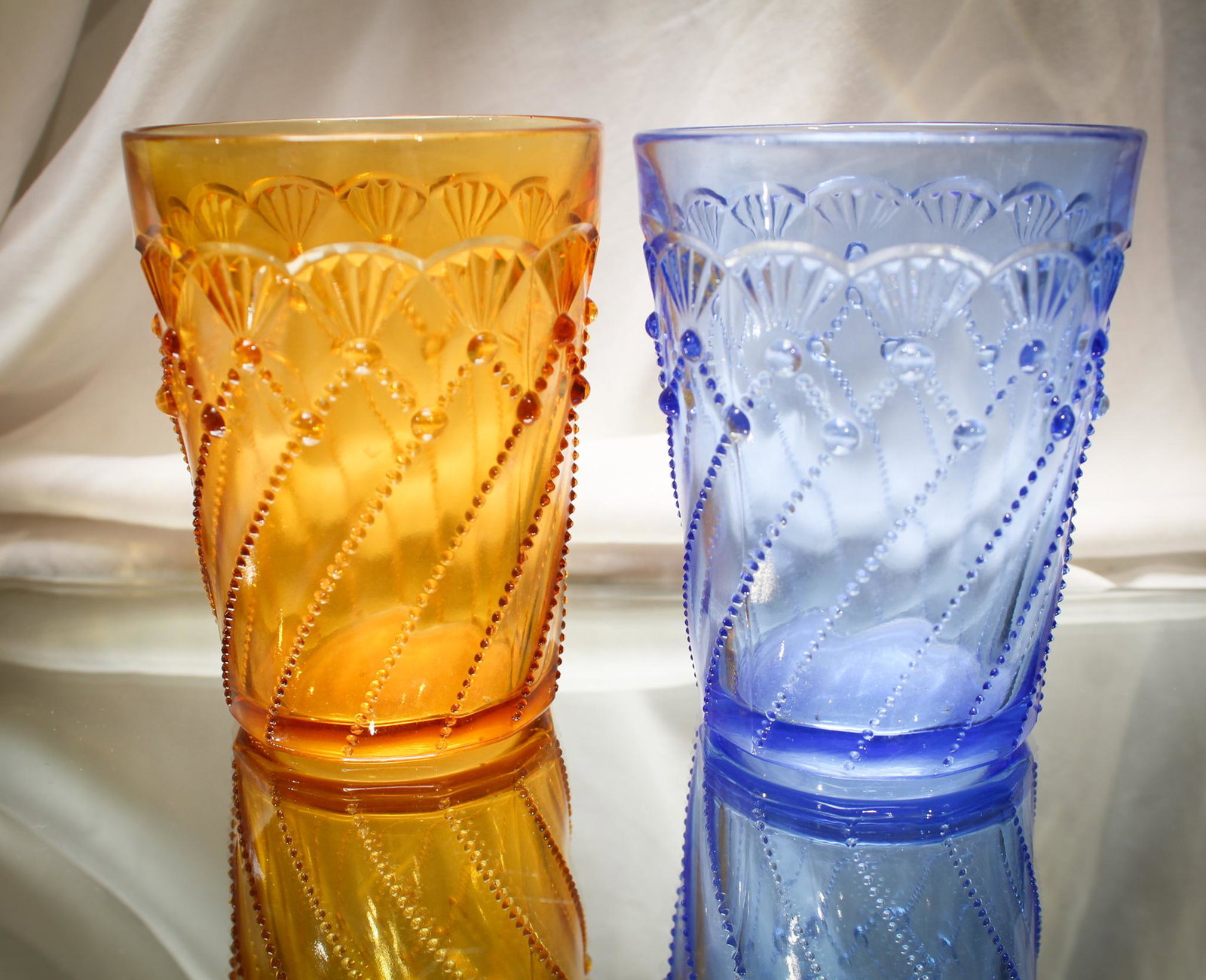 2 pc Lot Greentown Victorian Glass Tumblers: Two fine examples of Greentown Cord Drapery tumblers. One blue, and one Pooh Bear honey Amber. Each measures 4" tall.