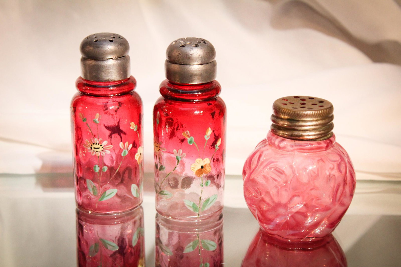 3 pc Lot Victorian Cranberry Enameled Opalesccent Shakers: Wonderful pair of rubina cranberry enameled salt shakers along with a cranberry opalescent daisy and fern shaker. So much wonderfulness in one lot. Niice examples of each as well. Tallest measures 4".